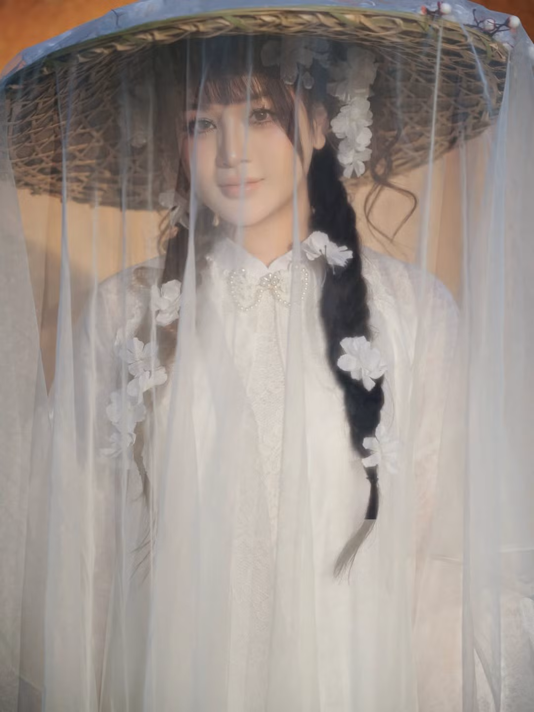 Hình ảnh Lyly Sury đội chiếc nón lá gắn dải voan mỏng và hoa trắng là khoảnh khắc đắt giá nhất. Nó không chỉ là món phụ kiện truyền thống mà còn tạo nên hiệu ứng "mờ ảo", tăng thêm phần bí ẩn và cuốn hút cho gương mặt. (Ảnh: IGNV)