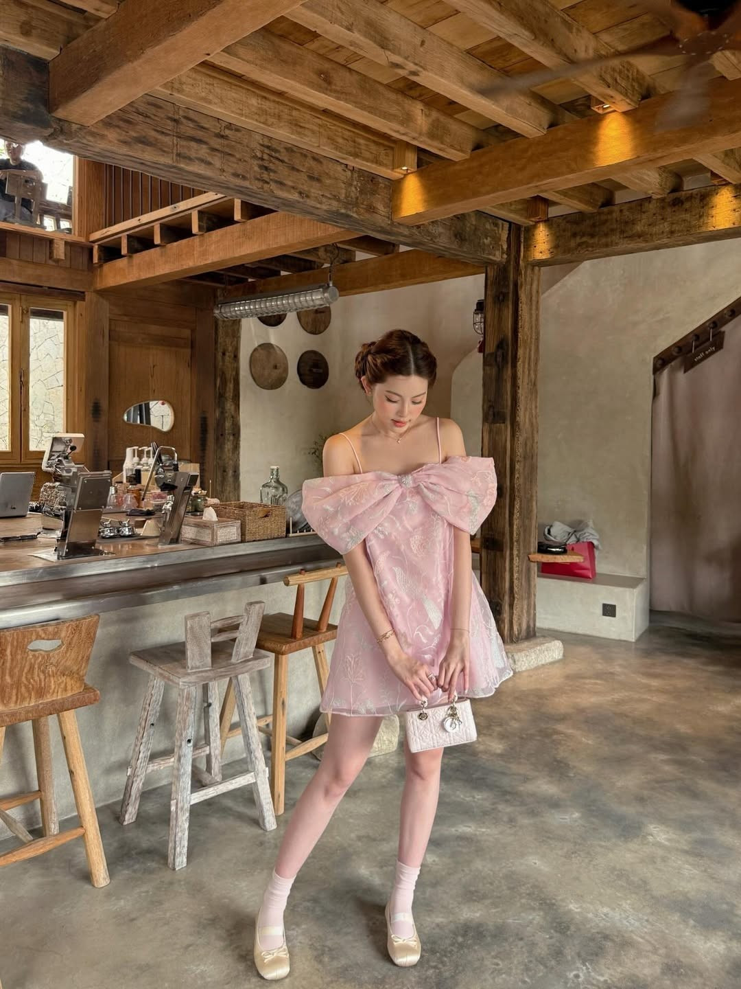 Bộ ảnh được thực hiện tại một quán cà trà mang phong cách mộc mạc với tông màu gỗ ấm và tường xi măng mài đặc trưng. Sự kết hợp giữa nét cổ điển của không gian và sự hiện đại của bộ trang phục tạo nên một tổng thể hài hòa. (Ảnh: IGNV)