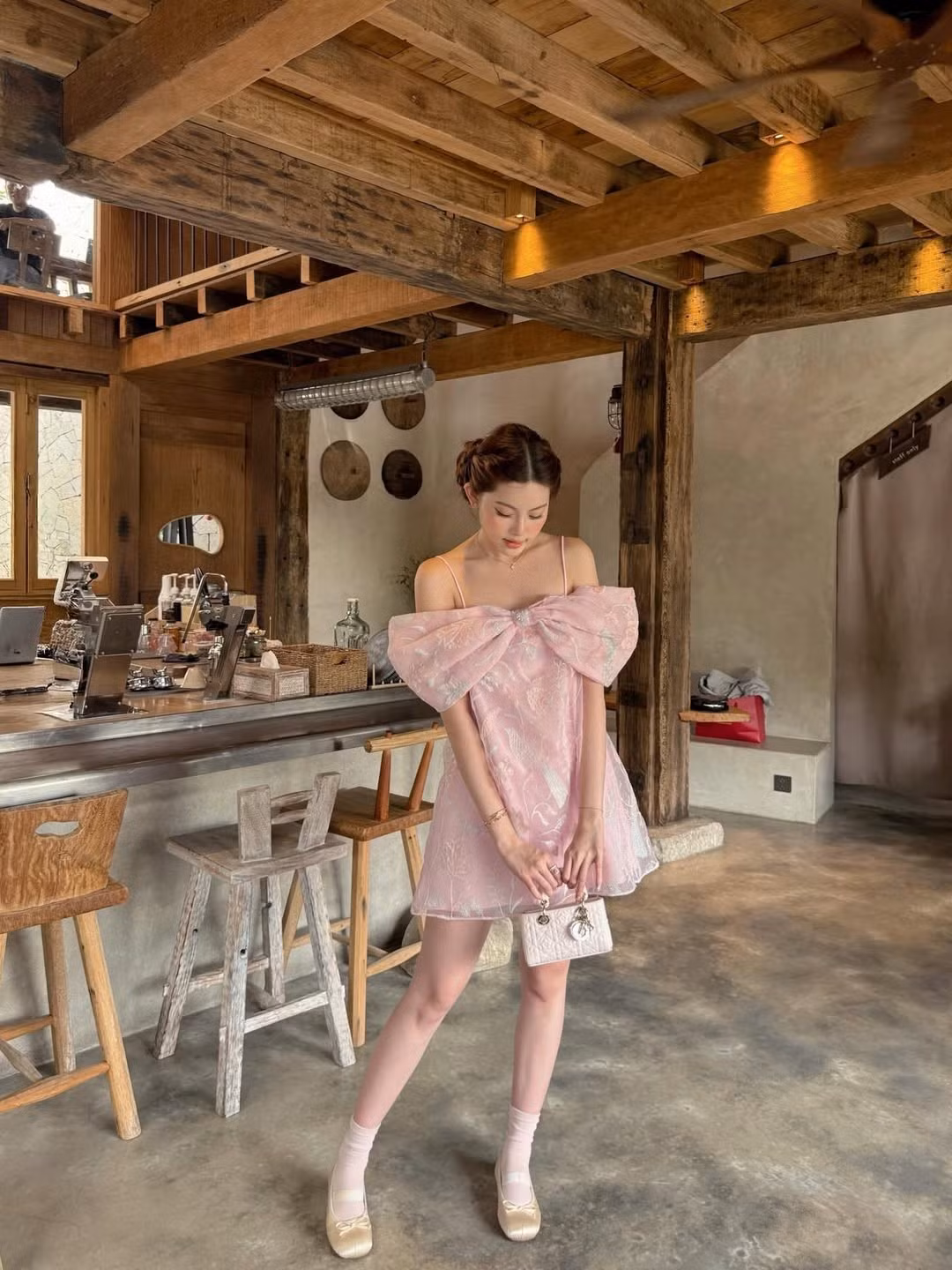 Bộ ảnh được thực hiện tại một quán cà trà mang phong cách mộc mạc với tông màu gỗ ấm và tường xi măng mài đặc trưng. Sự kết hợp giữa nét cổ điển của không gian và sự hiện đại của bộ trang phục tạo nên một tổng thể hài hòa. (Ảnh: IGNV)