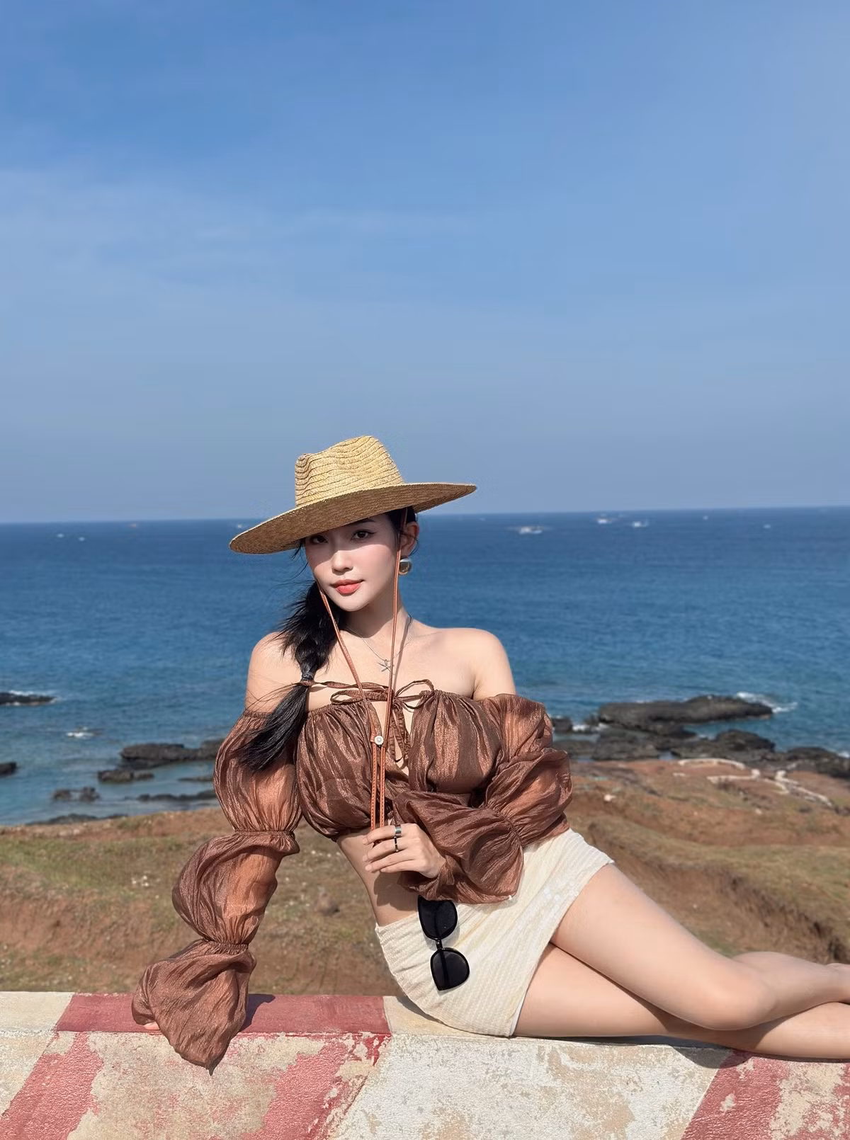 Bên cạnh đó, không thể không kể đến chiếc mũ cói rộng vành - item không thể thiếu khi đi biển. Huệ Chi đã chọn một chiếc mũ với thiết kế đơn giản nhưng vô cùng hiệu quả trong việc che nắng và tạo điểm nhấn thời trang (Ảnh: IGNV)
