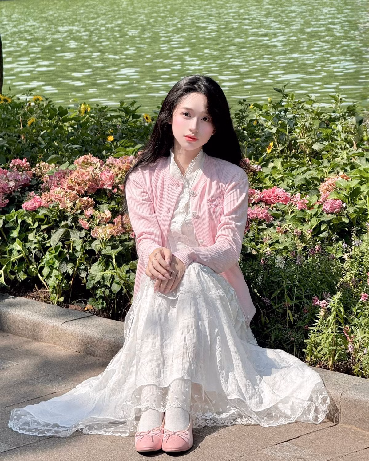 Cô khoác ngoài chiếc áo cardigan dệt kim màu hồng phấn, làm tôn lên sự nữ tính, dịu dàng. Đôi giày búp bê cùng màu hồng ton-sur-ton càng làm tăng thêm vẻ đáng yêu, yểu điệu. (Ảnh: FBNV)