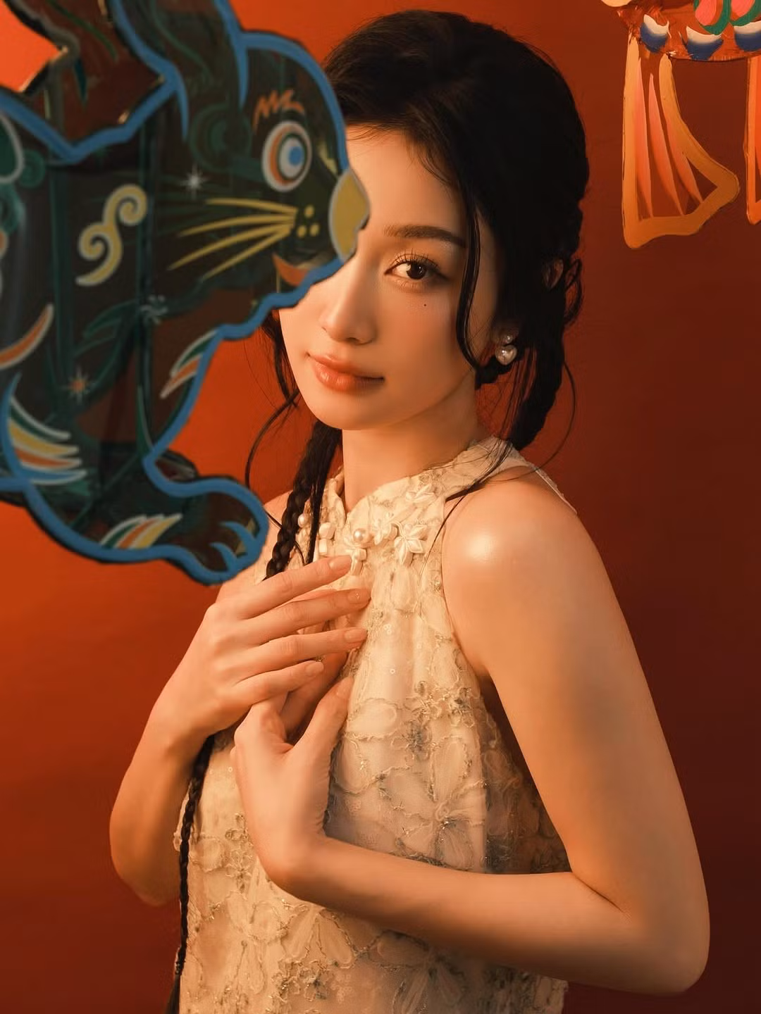 Với phông nền màu đỏ gạch ấm áp, Jun Vũ tạo dáng bên cạnh những chiếc lồng đèn giấy truyền thống hình con thỏ và con cá chép – những biểu tượng không thể thiếu của lễ hội này.