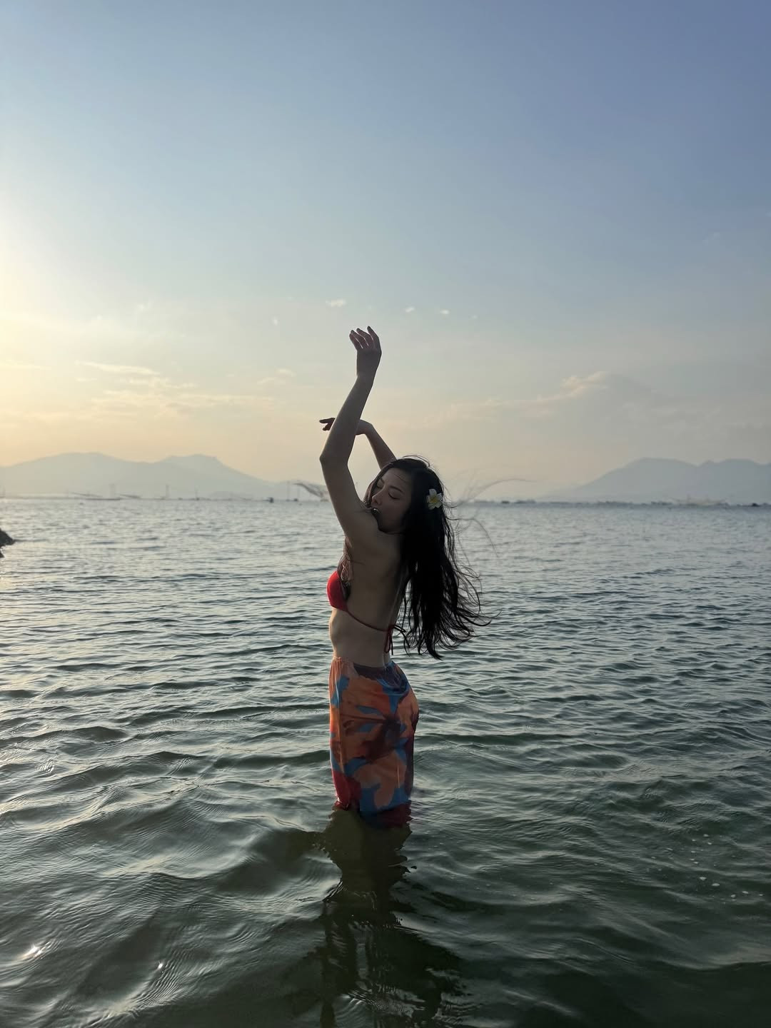 Điểm nhấn trong trang phục đi biển của cô chính là chiếc khăn sarong họa tiết sặc sỡ, được quấn khéo léo quanh hông tạo thành chân váy ấn tượng.