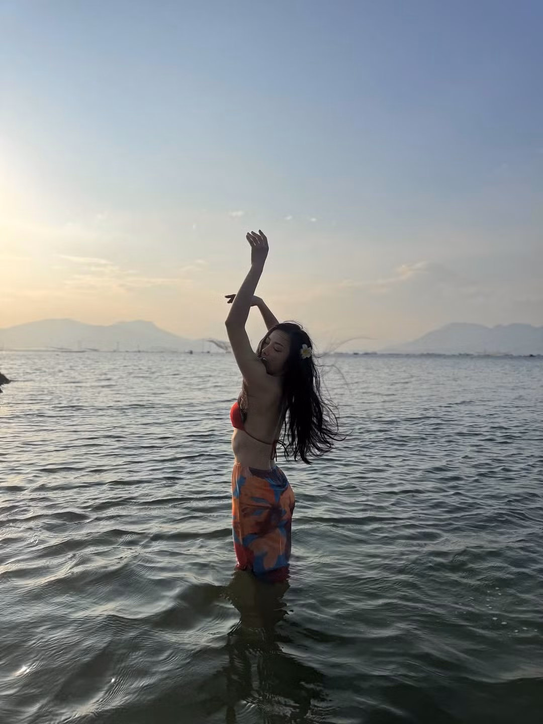 Điểm nhấn trong trang phục đi biển của cô chính là chiếc khăn sarong họa tiết sặc sỡ, được quấn khéo léo quanh hông tạo thành chân váy ấn tượng.