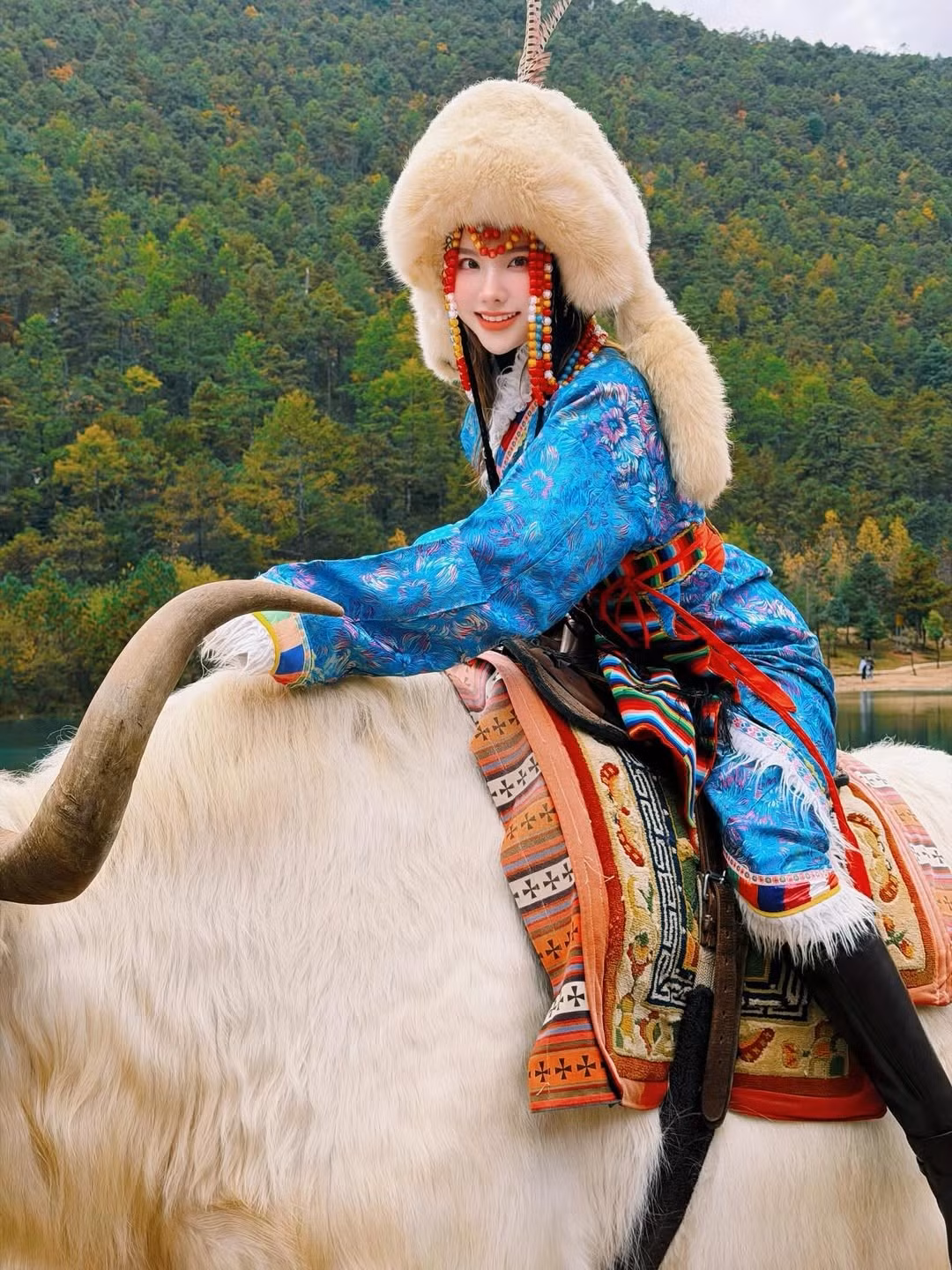 Tâm điểm của bộ ảnh chính là khoảnh khắc Hạnh Sino duyên dáng tạo dáng trên lưng chú bò Yak (bò Tây Tạng) trắng muốt với cặp sừng lớn, nổi bật giữa bãi gỗ ven hồ. (Ảnh: IGNV)