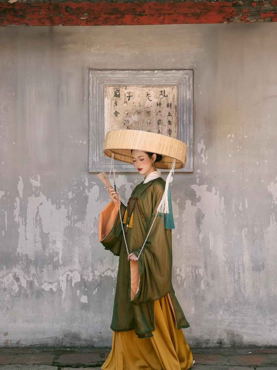 Bộ ảnh được thực hiện tại một không gian mang đậm kiến trúc cổ với tường vôi bạc màu, những bức hoành phi chữ Hán và hồ sen tĩnh lặng. (Ảnh: IGNV)