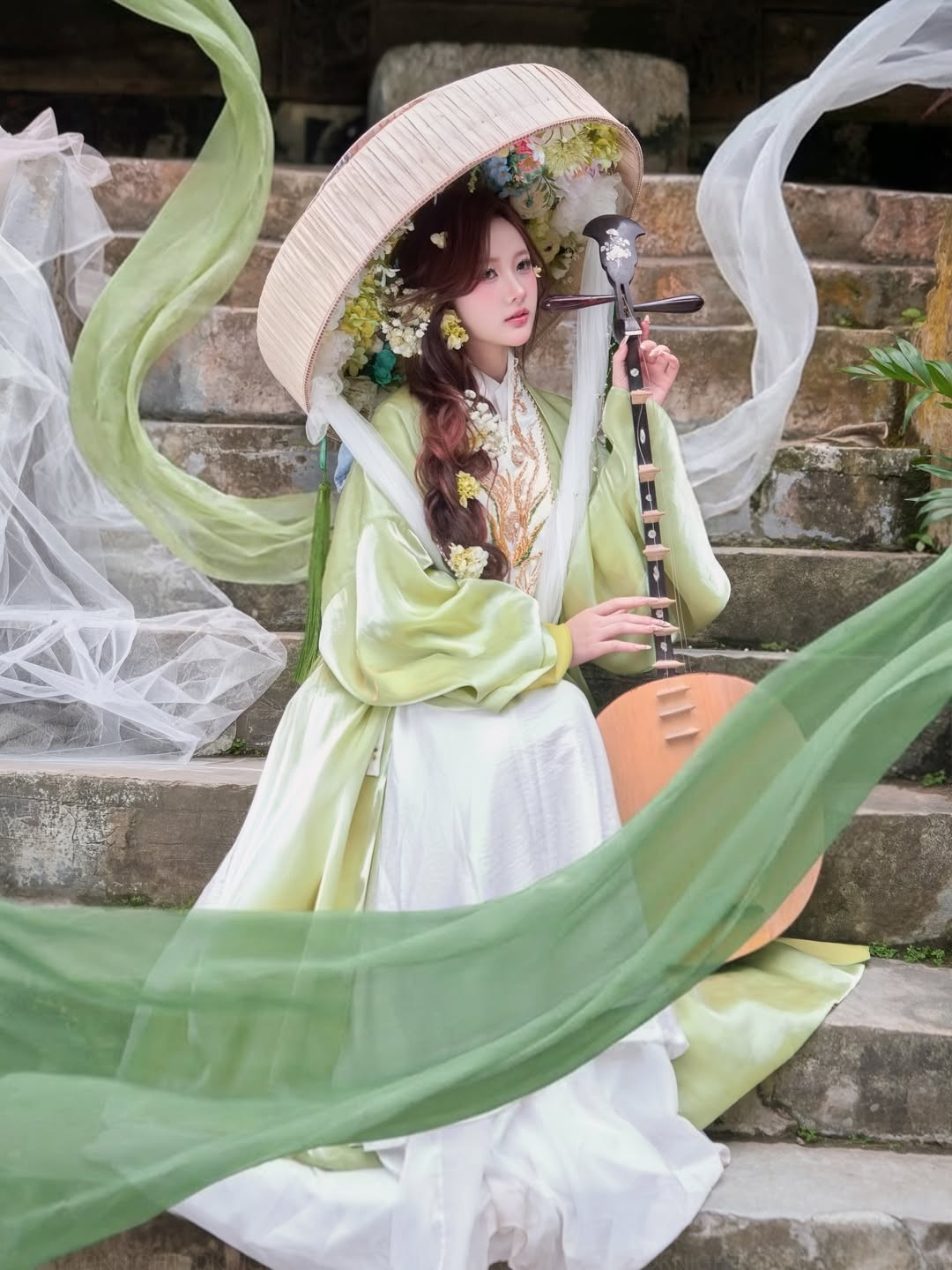 Bên cạnh đó, chiếc nón quai thao cách điệu được đính thêm những đóa hoa tươi và lớp voan trắng mỏng đã tạo điểm nhấn cho bộ ảnh. Khi ánh sáng xuyên qua lớp voan, gương mặt của Diệu Linh hiện lên mờ ảo, tạo nên vẻ đẹp thoát tục, mong manh.(Ảnh: IGNV)