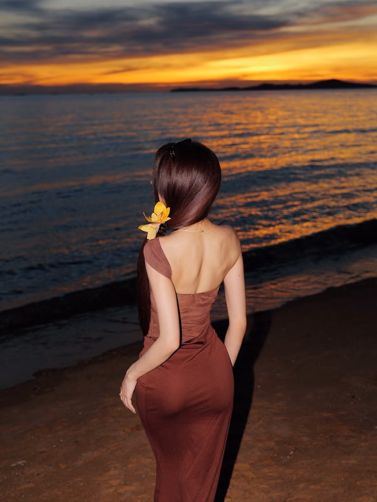 Khi hoàng hôn buông xuống, người mẫu chuyển sang một phong cách khác gợi cảm và bí ẩn hơn. Cô xuất hiện trong chiếc váy ôm sát màu nâu socola với thiết kế lệch vai độc đáo. (Ảnh: Facebook Janet Kanokwan Saesim)