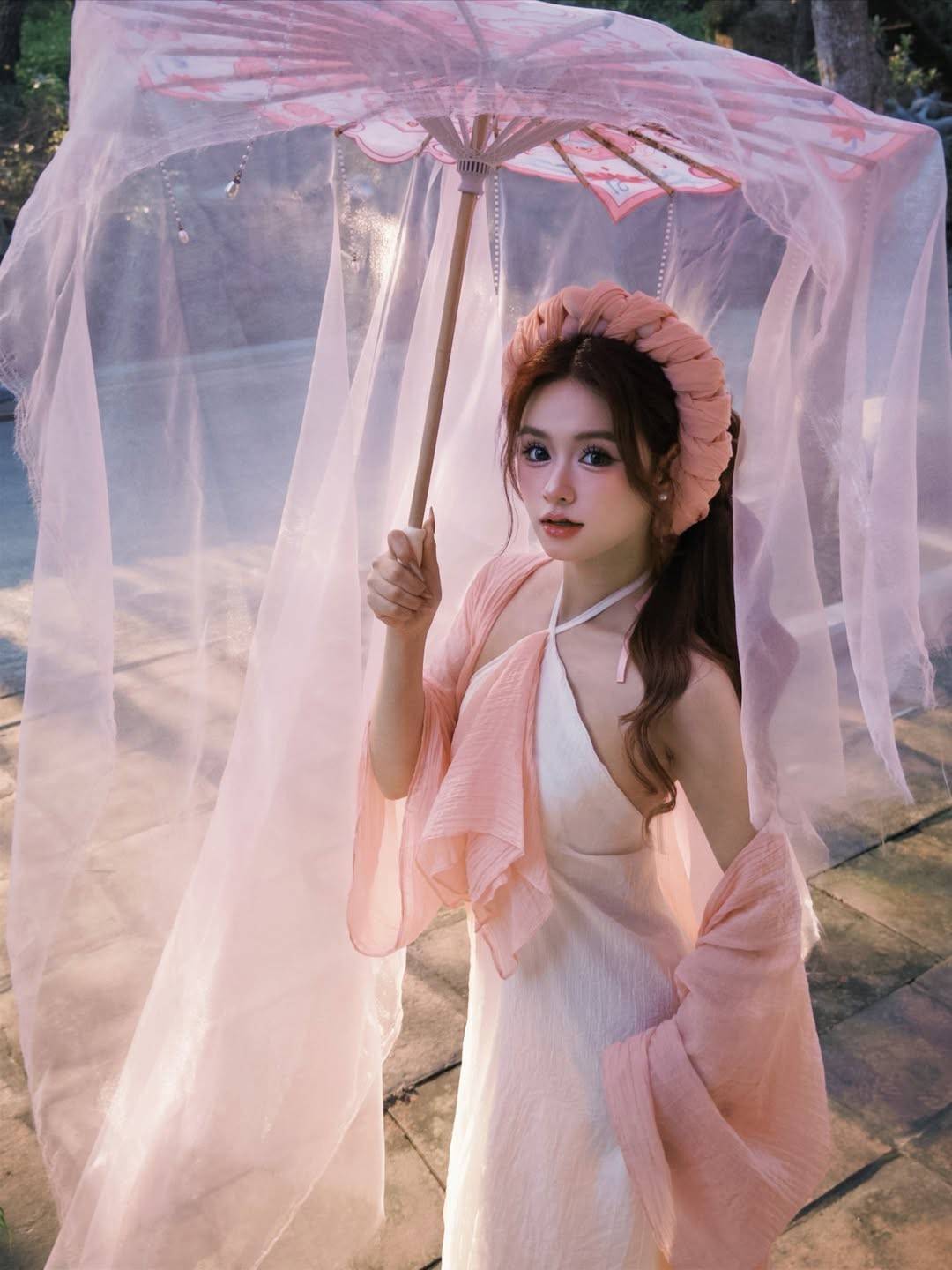 Trong bộ ảnh, Lê Na lựa chọn trang phục cách tân lấy cảm hứng từ áo yếm truyền thống với tông màu trắng - hồng pastel chủ đạo. Sự kết hợp giữa lụa mềm và voan mỏng tạo nên độ bay bổng, giúp cô nàng khoe khéo bờ vai trần thon thả. (Ảnh: IGNV)