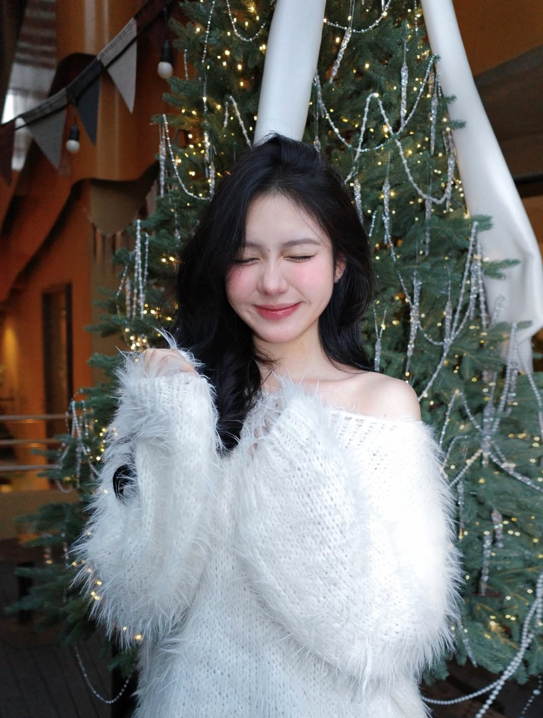 Không chọn những tông màu đỏ rực rỡ truyền thống, cô nàng xuất hiện trong chiếc áo len trễ vai màu trắng tinh khôi với chất liệu lông xù mềm mại. Thiết kế này khéo léo khoe trọn bờ vai trần thon thả và xương quai xanh quyến rũ nhưng vẫn giữ được nét kín đáo, thanh lịch. (Ảnh: IGNV)