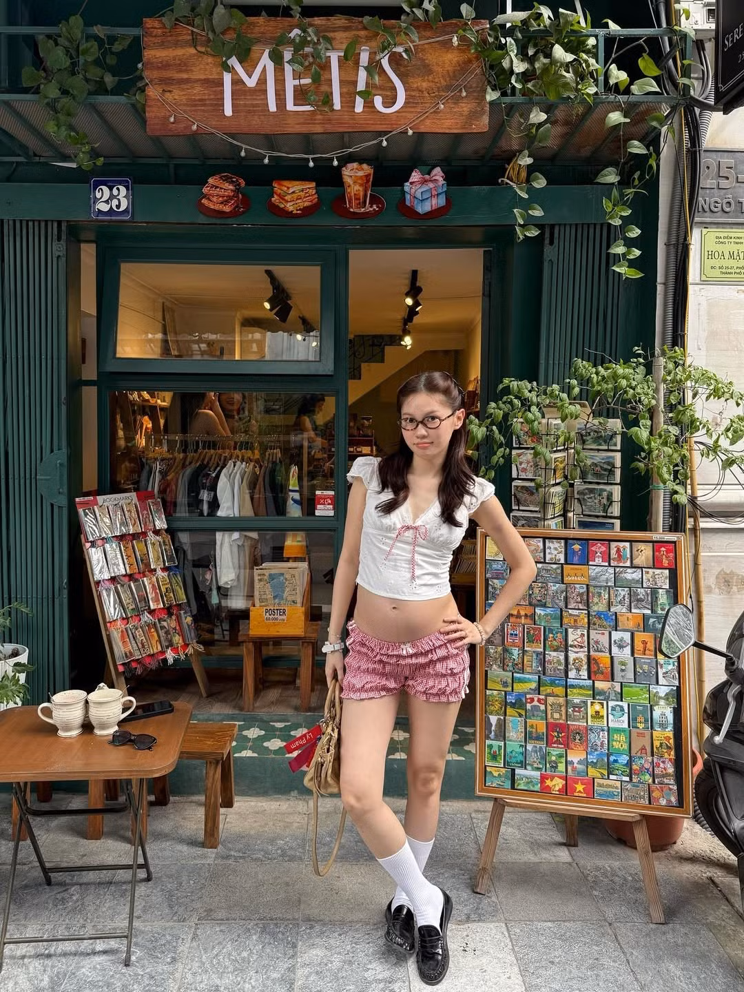 Cô chọn chiếc áo croptop trắng phối cùng quần short kẻ caro đỏ, khoe khéo vòng eo đang dần lớn nhưng vẫn giữ được nét thanh thoát.