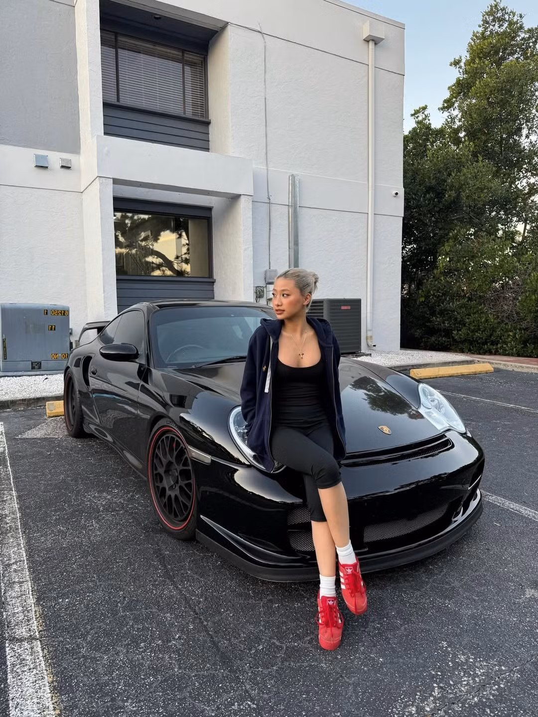 Gây ấn tượng mạnh nhất là khoảnh khắc Louis Phạm tạo dáng đầy thần thái bên chiếc Porsche thể thao màu đen hầm hố, cô tạo dáng nửa ngồi nửa tựa trên nắp capo của chiếc xe. (Ảnh: IGNV)