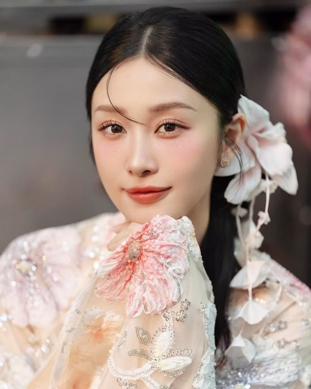 Những đóa hoa 3D mang tông màu hồng pastel, trắng và xanh nhạt được điểm xuyết bằng kim sa lấp lánh, tạo hiệu ứng thị giác như một vườn xuân đang nở rộ trên chính tà áo. (Ảnh: IGNV)