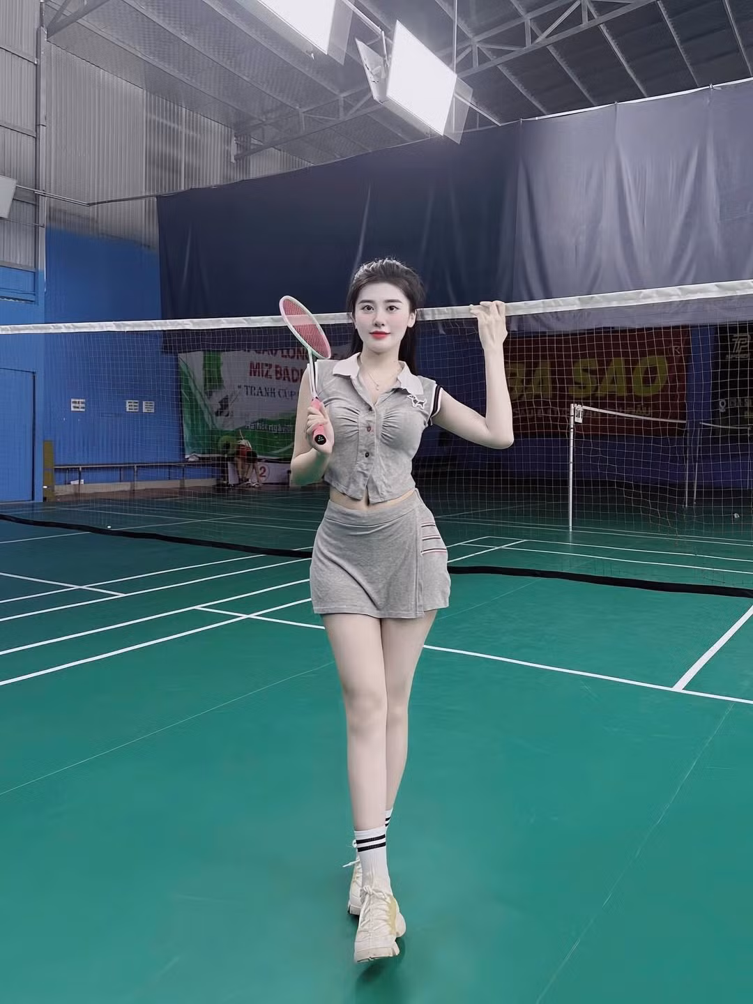 Trong loạt ảnh mới đăng tải, hot girl sinh năm 1996 diện một set đồ thể thao màu xám nhạt bao gồm áo crop top sát nách có cổ polo và chân váy ngắn năng động. (Ảnh: IGNV)