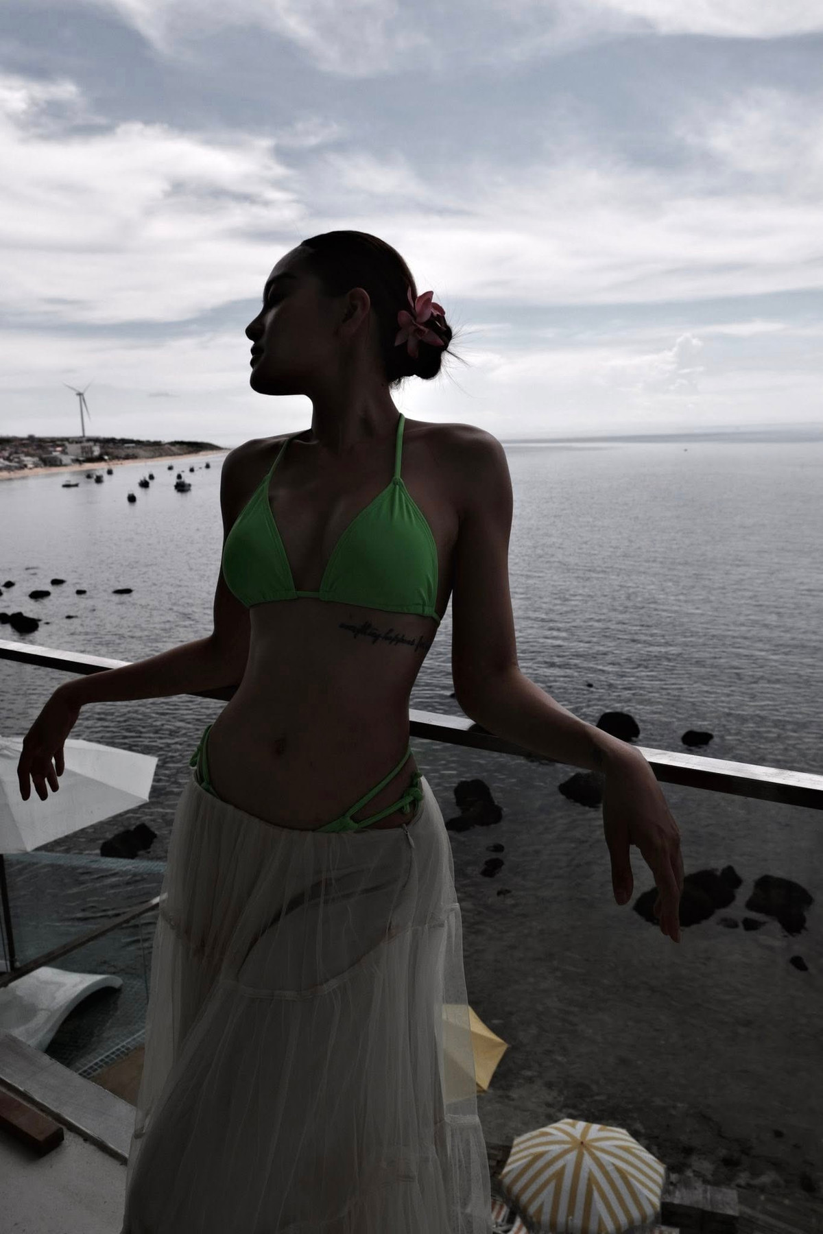 Bikini màu xanh neon – một gam màu khó nhằn nhưng cực kỳ nổi bật – chính là điểm nhấn thị giác mạnh mẽ, giúp cô nổi bật giữa bối cảnh đá đen và biển xanh mênh mông.