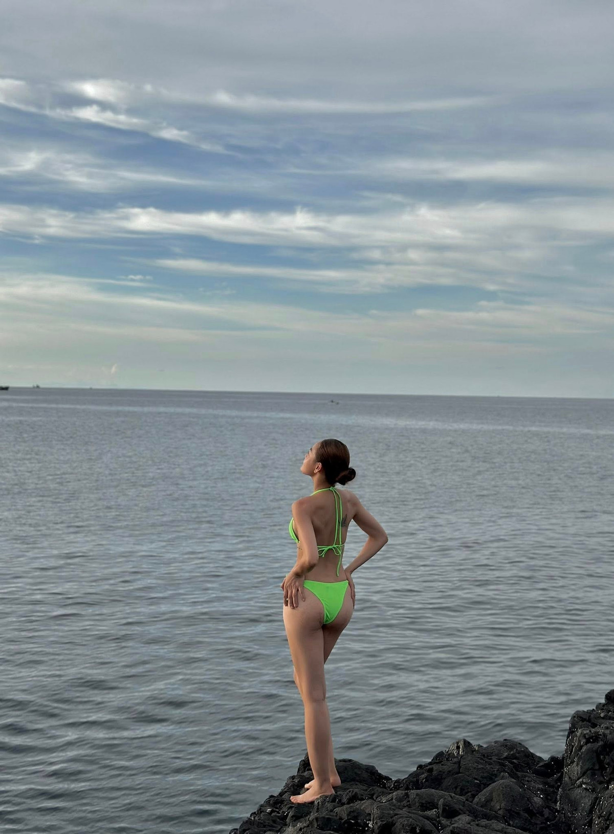 Trên nền đá đen thô ráp của bãi biển, cô trở nên nổi bật như một nàng thơ hiện đại vừa dịu dàng, vừa mạnh mẽ.