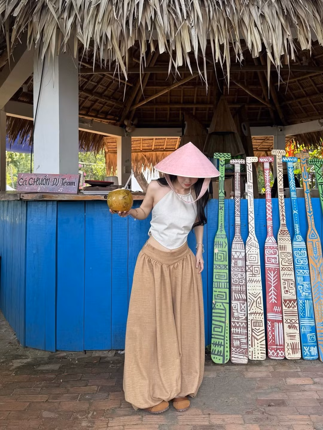 Trong một loạt ảnh khác, Thúy Kiều diện một chiếc áo yếm màu trắng ngà kết hợp với quần ống rộng màu nâu đất. Kiểu áo yếm cổ điển, hở vai và lưng, mang lại cảm giác mát mẻ, phóng khoáng và phù hợp với không khí biển. Màu trắng ngà tạo sự nhẹ nhàng, tinh tế. (Ảnh: IGNV)