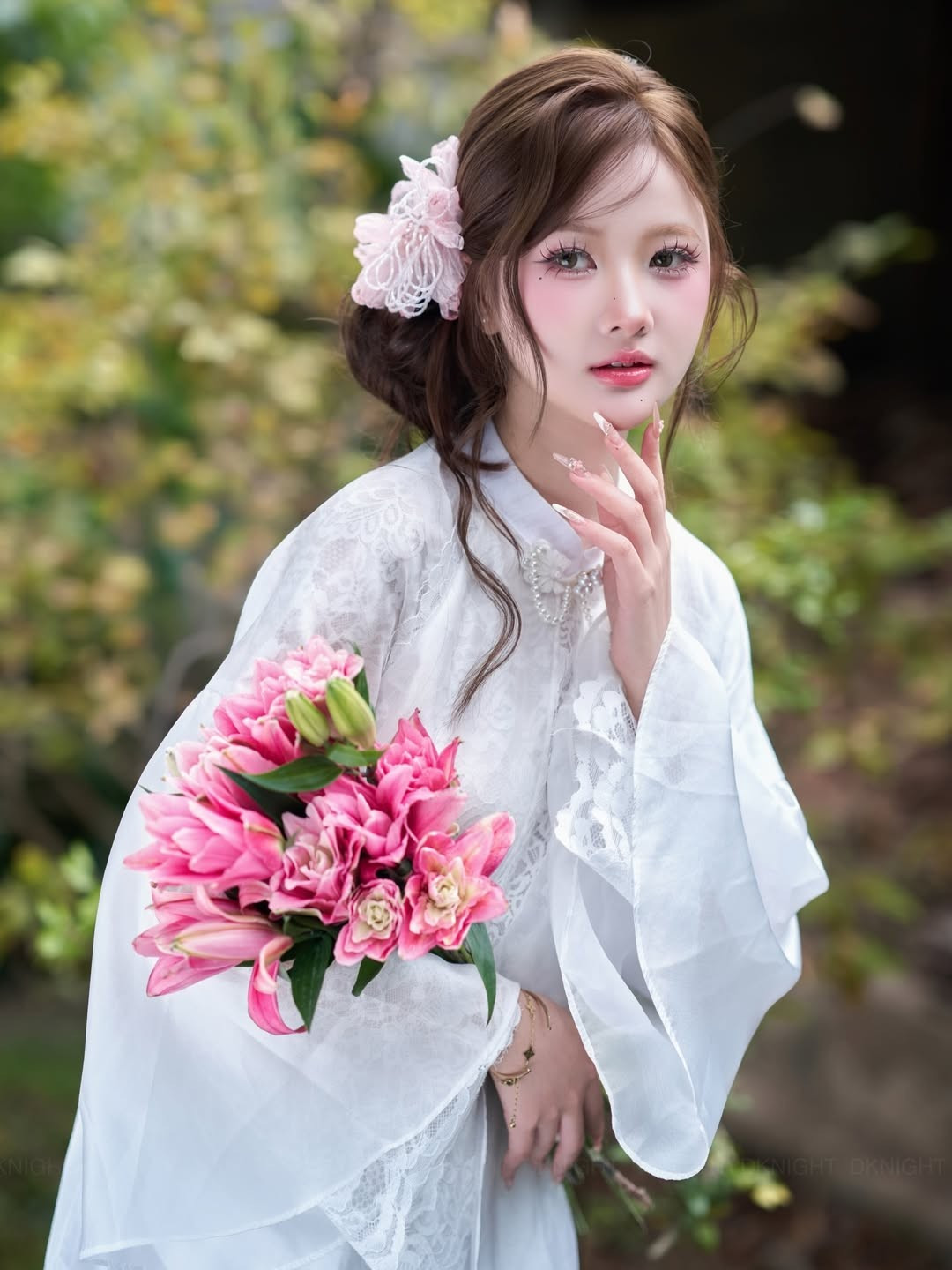 Cùng với đó là bó hoa ly cầm tay, điểm xuyết sắc hồng rực rỡ trên nền trắng tinh khôi của áo dài, tạo điểm nhấn thị giác mạnh mẽ.(Ảnh: IGNV)