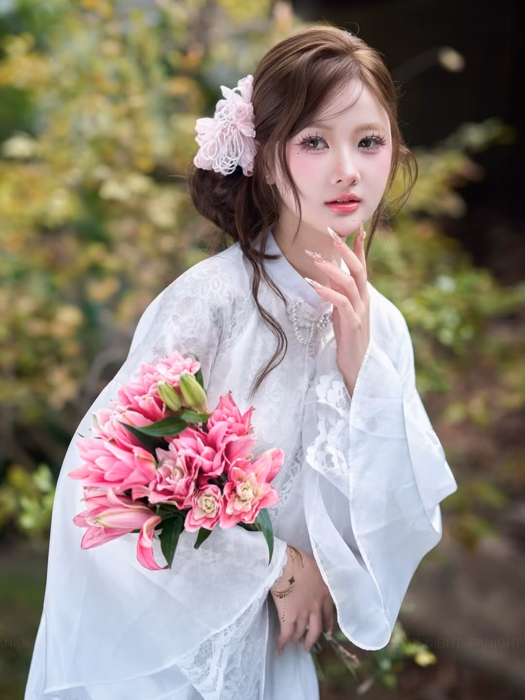 Cùng với đó là bó hoa ly cầm tay, điểm xuyết sắc hồng rực rỡ trên nền trắng tinh khôi của áo dài, tạo điểm nhấn thị giác mạnh mẽ.(Ảnh: IGNV)