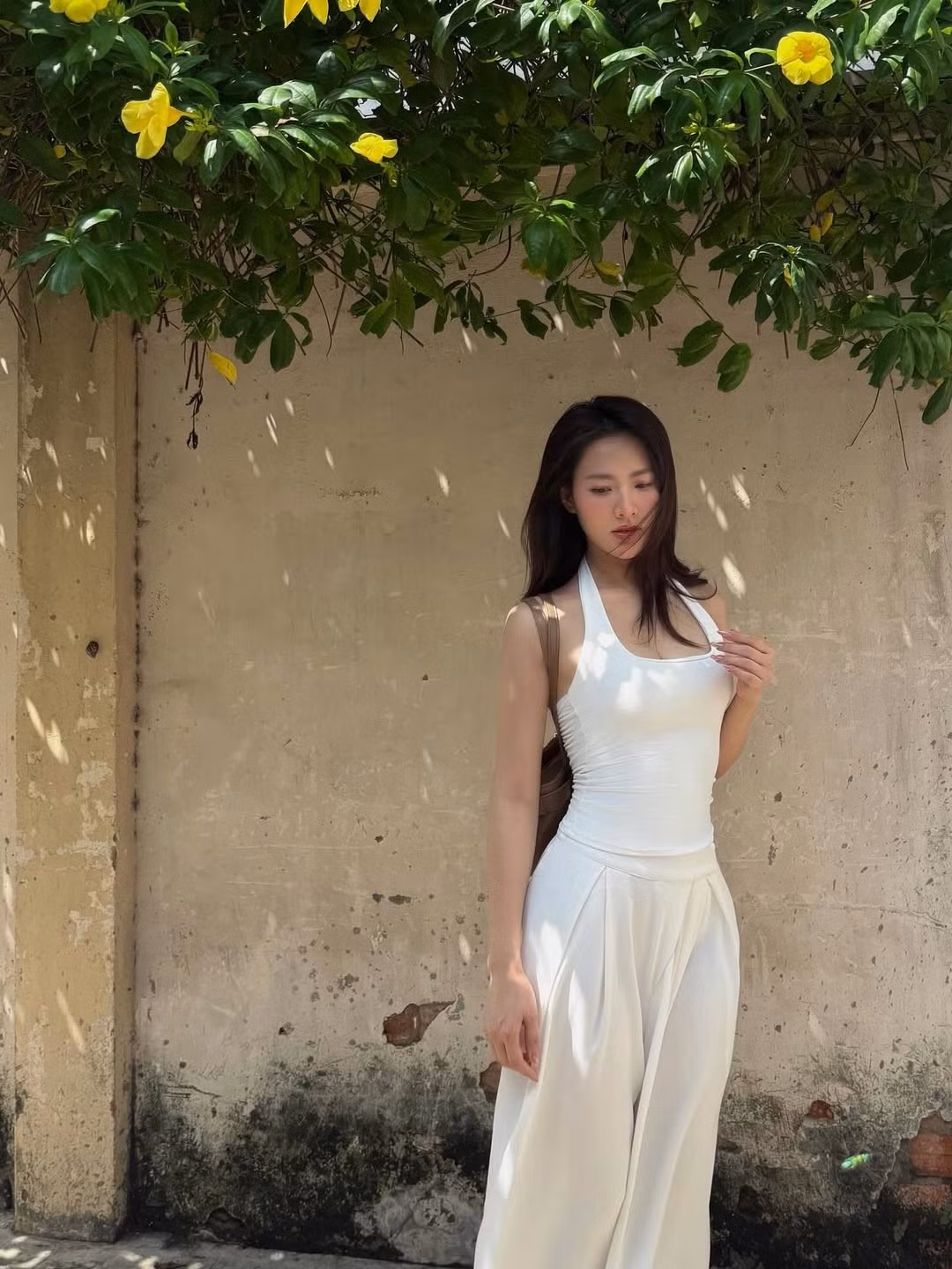 Phụ kiện đi kèm là một chiếc túi xách màu nâu, tạo nên điểm nhấn tinh tế cho tổng thể trang phục. (Ảnh: IGNV)