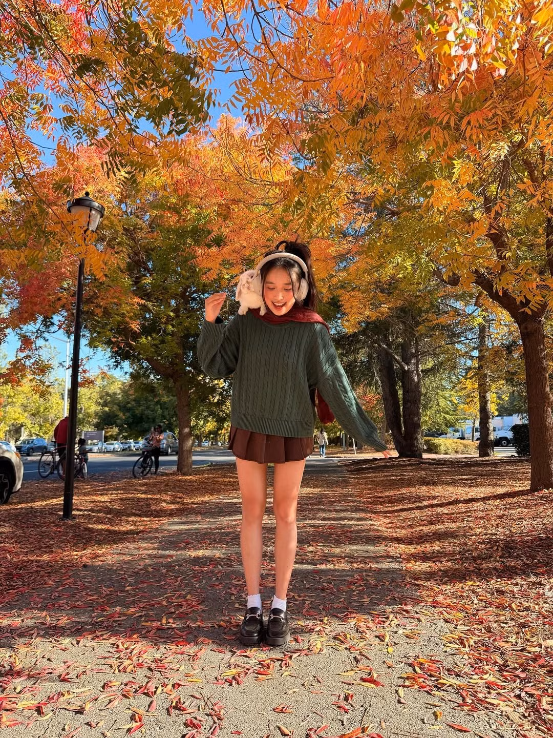 Trong bộ ảnh, Jenny Huỳnh tái hiện lại hình ảnh đặc trưng của "Lofi girl" với: set đồ bao gồm chiếc áo len vặn thừng màu xanh lá đậm, chân váy màu đỏ trầm cùng khăn quàng cổ cùng tone. (Ảnh: FBNV)