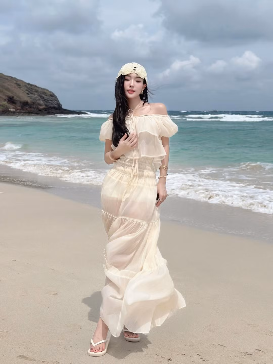 Trong loạt ảnh mới được đăng tải lên trang cá nhân, Huệ Chi khoác lên mình một chiếc đầm maxi màu kem nhẹ nhàng, bồng bềnh, thả dáng giữa phông nền biển xanh, cát trắng. (Ảnh: IGNV)