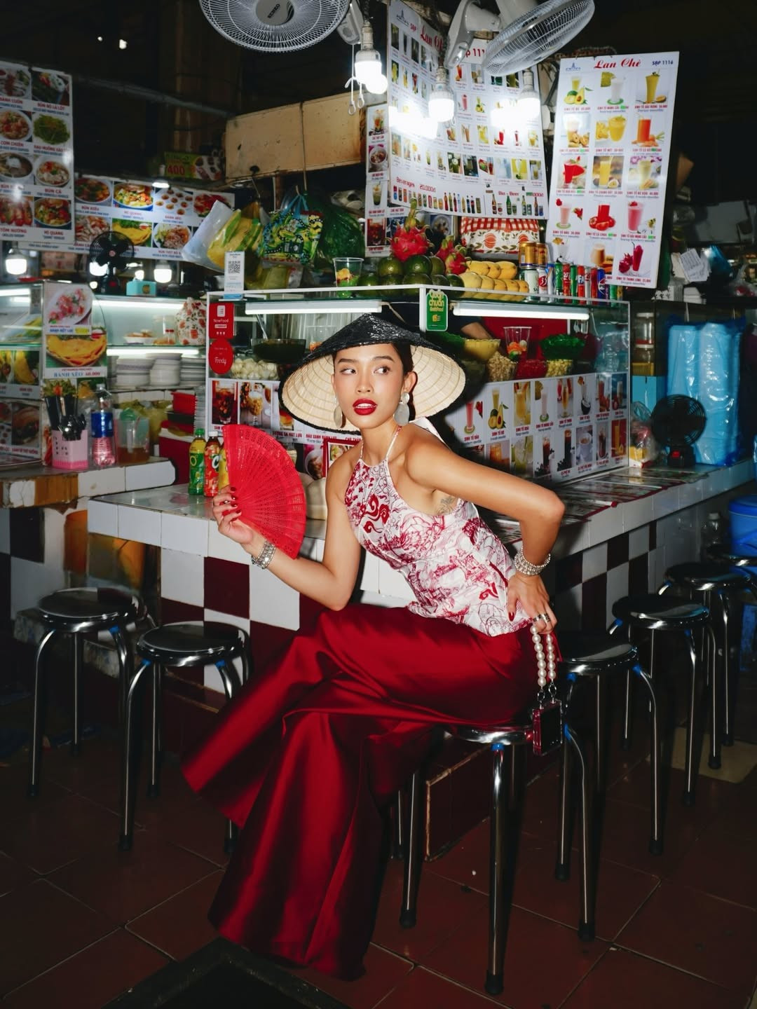 Dưới ống kính mang hơi hướng phim ảnh, Lilthu lúc thì e ấp với quạt giấy đỏ, lúc lại cười rạng rỡ, tinh nghịch khi tương tác với những người bán hàng. (Ảnh IGNV)