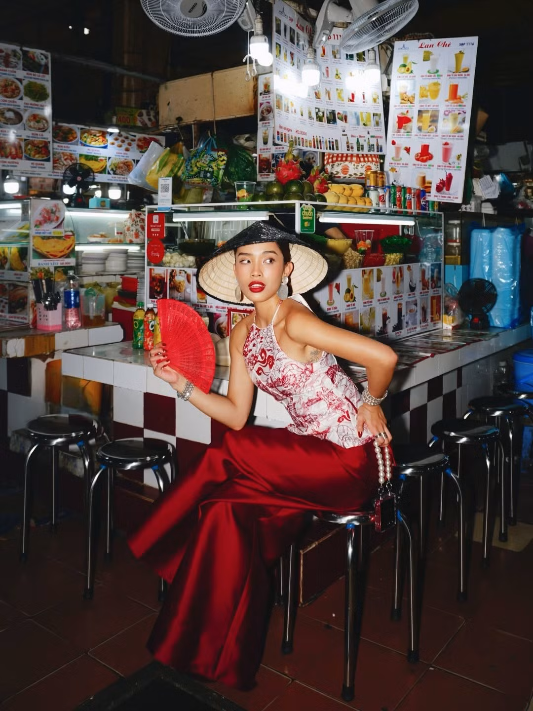 Dưới ống kính mang hơi hướng phim ảnh, Lilthu lúc thì e ấp với quạt giấy đỏ, lúc lại cười rạng rỡ, tinh nghịch khi tương tác với những người bán hàng. (Ảnh IGNV)