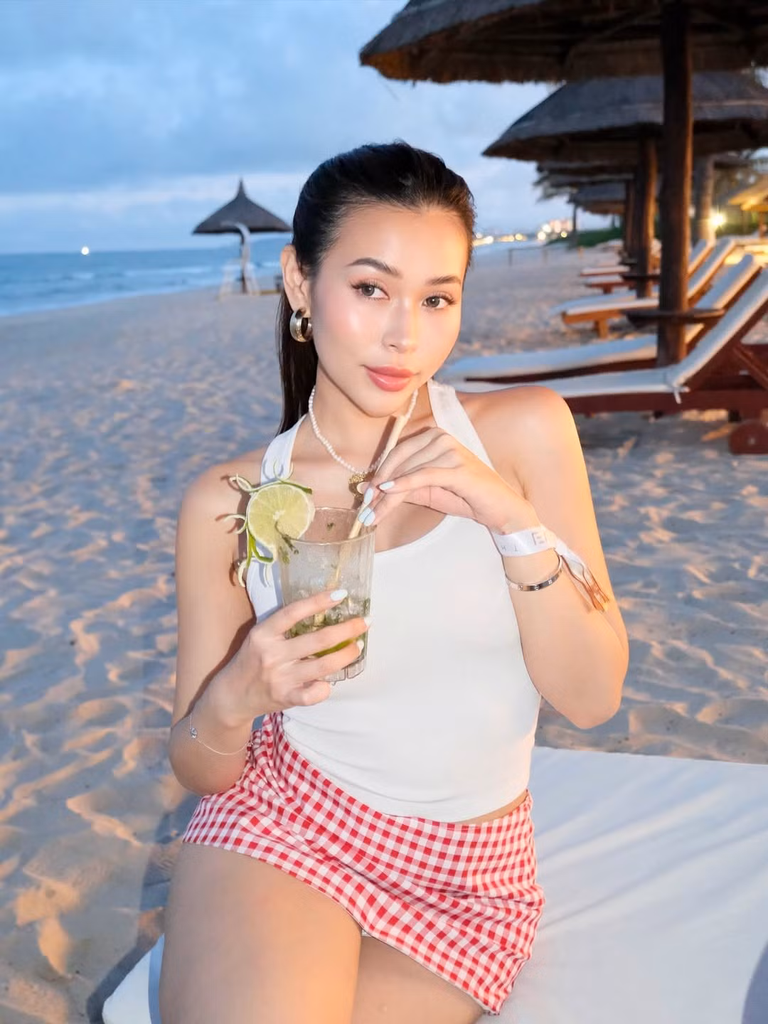 Điểm nhấn chính là chiếc chân váy mini kẻ ô Gingham tông màu đỏ và trắng. Họa tiết kẻ ô này mang hơi hướng cổ điển, gợi nhớ đến phong cách thời trang thập niên 50-60. Chân váy ngắn giúp tôn lên đôi chân dài và tạo vẻ ngoài trẻ trung, tinh nghịch.