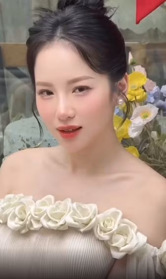 Vẻ đẹp ngọt ngào của Loan Barbie càng được tôn lên nhờ lối trang điểm nhẹ nhàng với má hồng, môi đỏ cam và kiểu tóc búi cao gọn gàng.