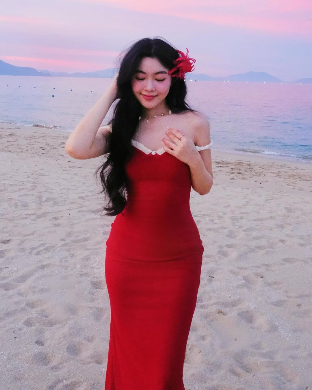 Điểm nhấn đặc biệt trong set ảnh là chiếc hoa đỏ được cài trên tóc, tạo nên vẻ đẹp vừa dịu dàng vừa quyến rũ.