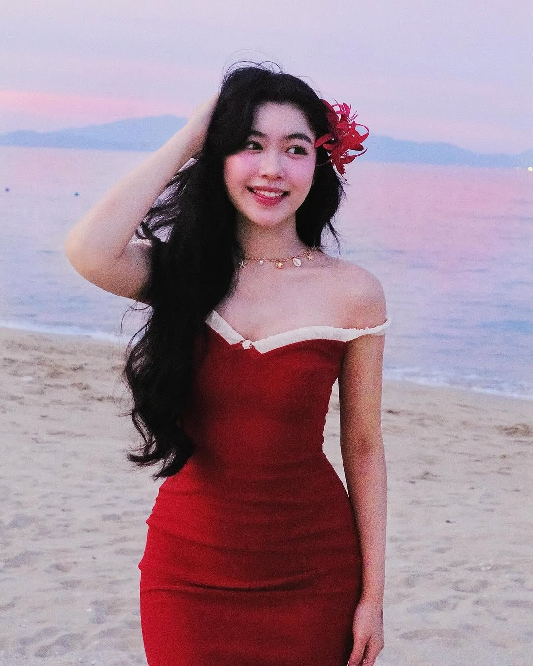 Cô nàng diện chiếc đầm đỏ trễ vai ôm sát, tôn lên làn da trắng ngần và đường cong quyến rũ.