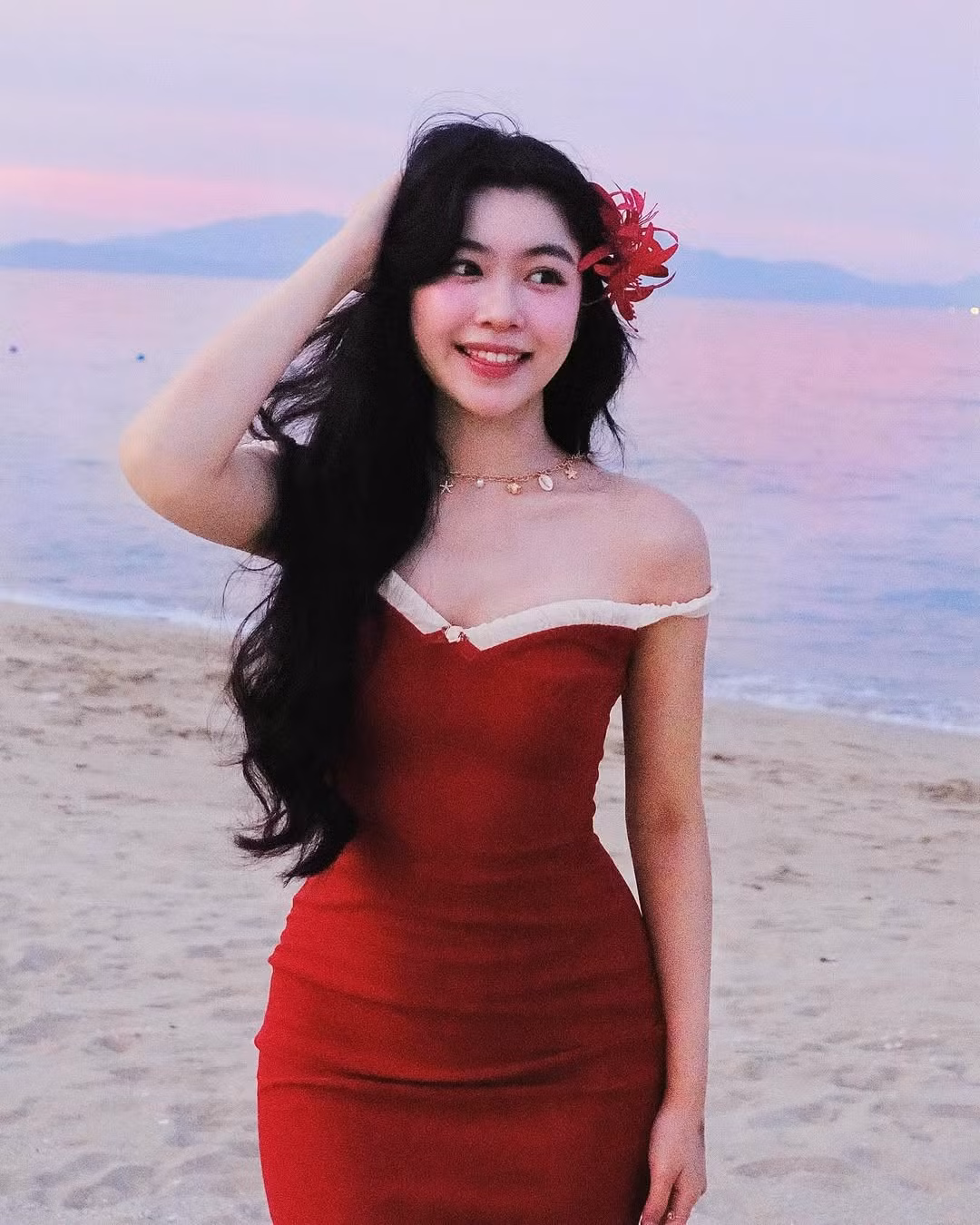 Cô nàng diện chiếc đầm đỏ trễ vai ôm sát, tôn lên làn da trắng ngần và đường cong quyến rũ.