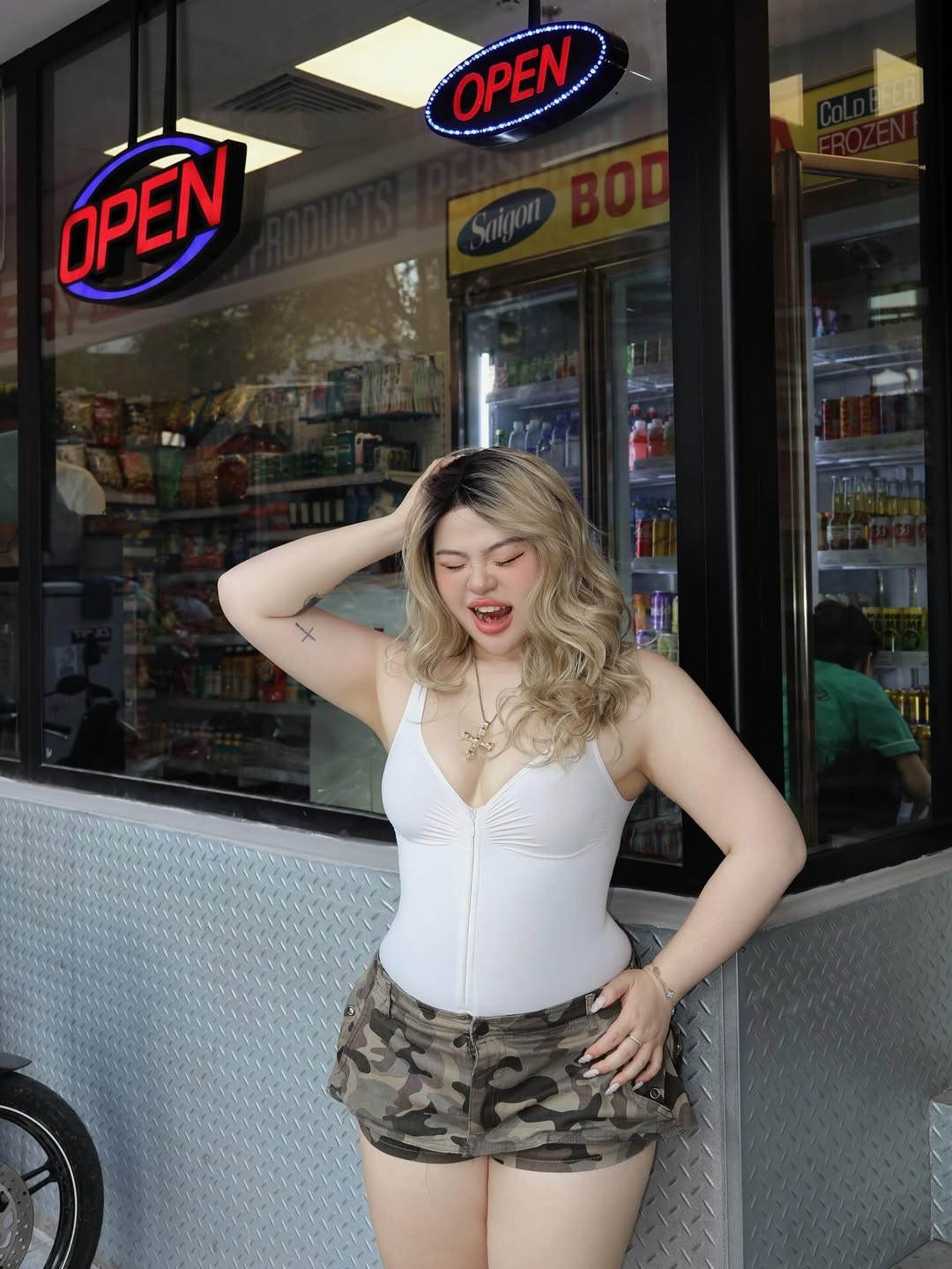 Thay vì khéo léo che đậy khuyết điểm bằng những bộ đồ rộng thùng thình, Cố Hữu Vi chọn cho mình phong cách Y2K hiện đại với áo bodysuit trắng tinh khôi, ôm sát cơ thể phối cùng chân váy ngắn họa tiết camo.(Ảnh: IGNV)