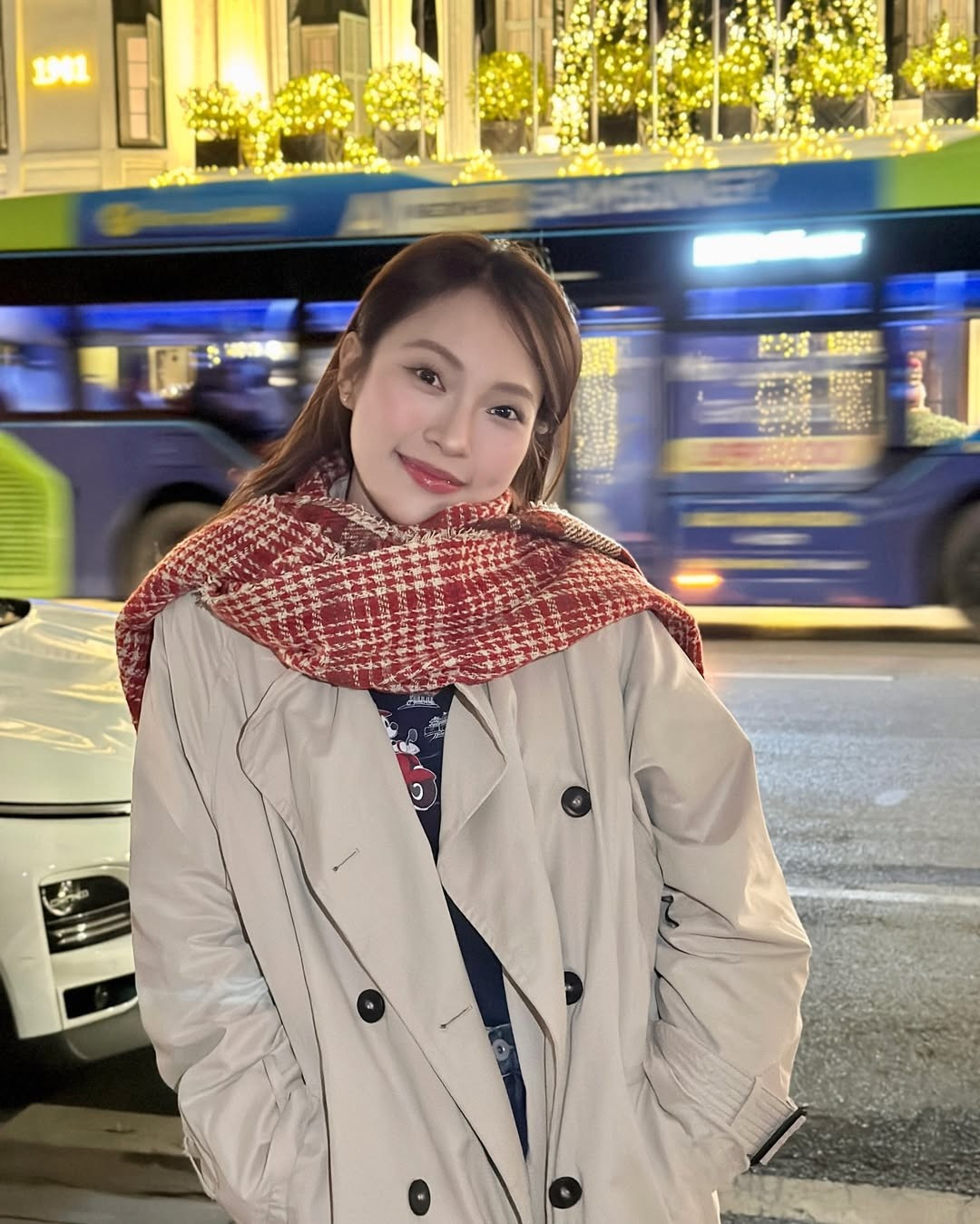Trong bộ ảnh, cô nàng lựa chọn một chiếc trench coat màu beige cổ điển - món đồ "bất hủ" của mùa đông, kết hợp cùng chiếc khăn len họa tiết kẻ caro đỏ trắng bản to nổi bật. (Ảnh: IGNV)