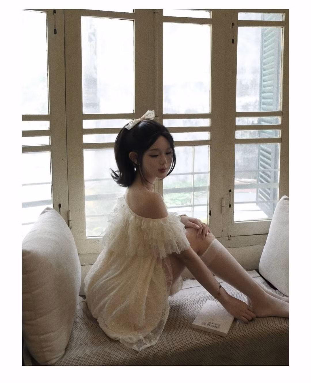 Cô nàng chọn diện một chiếc váy ngắn bồng bềnh, chất liệu ren màu trắng kem. Thiết kế nổi bật với phần trễ vai giúp cô khoe khéo bờ vai trần mảnh mai, xương quai xanh quyến rũ, làm tăng thêm vẻ gợi cảm tinh tế. (Ảnh: IGNV)