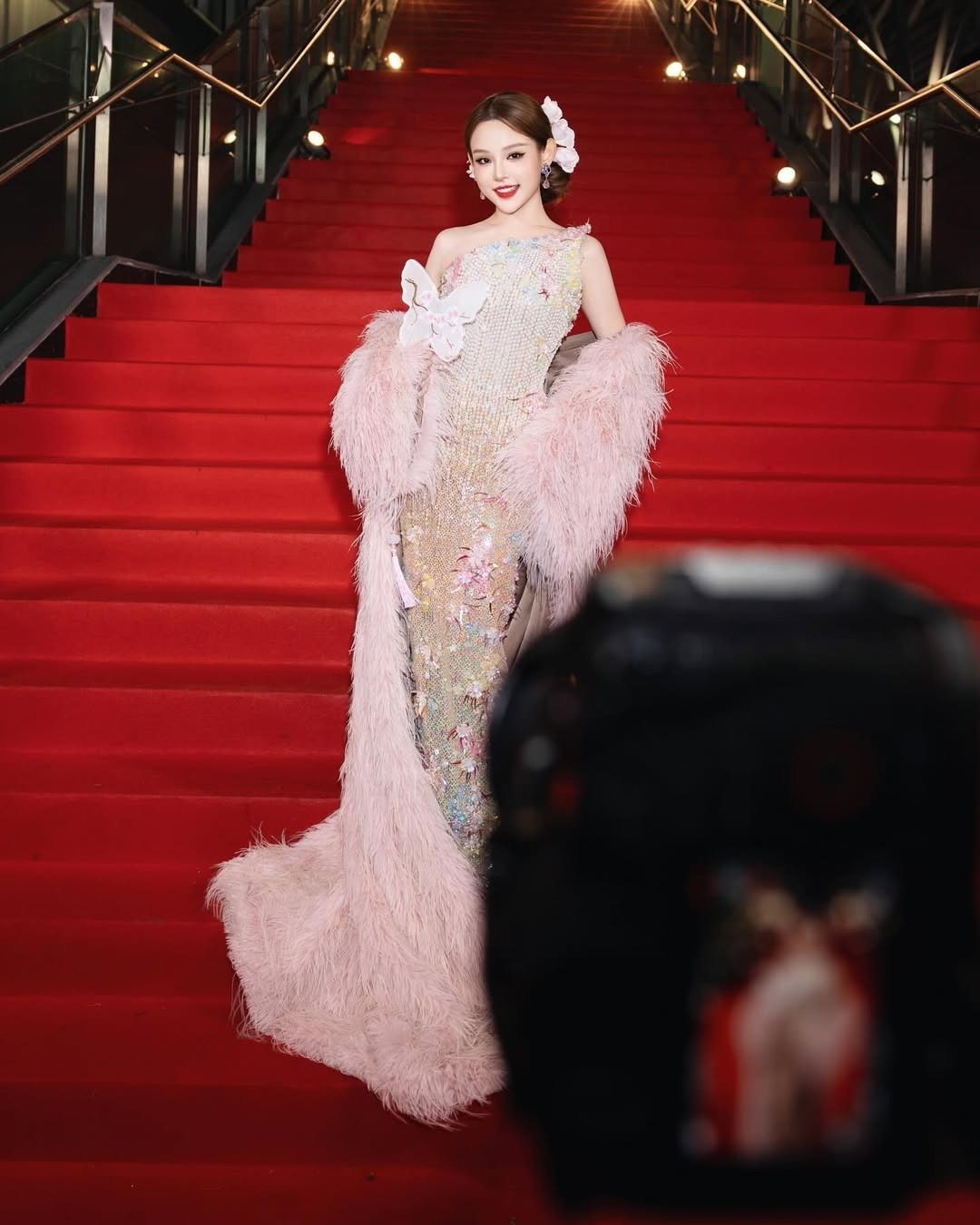 Trên tay cô là chiếc quạt hình bướm được thêu dệt tinh xảo, một món phụ kiện mang đậm nét Á Đông đương đại, hoàn thiện tổng thể diện mạo kiêu sa. (Ảnh: IGNV)