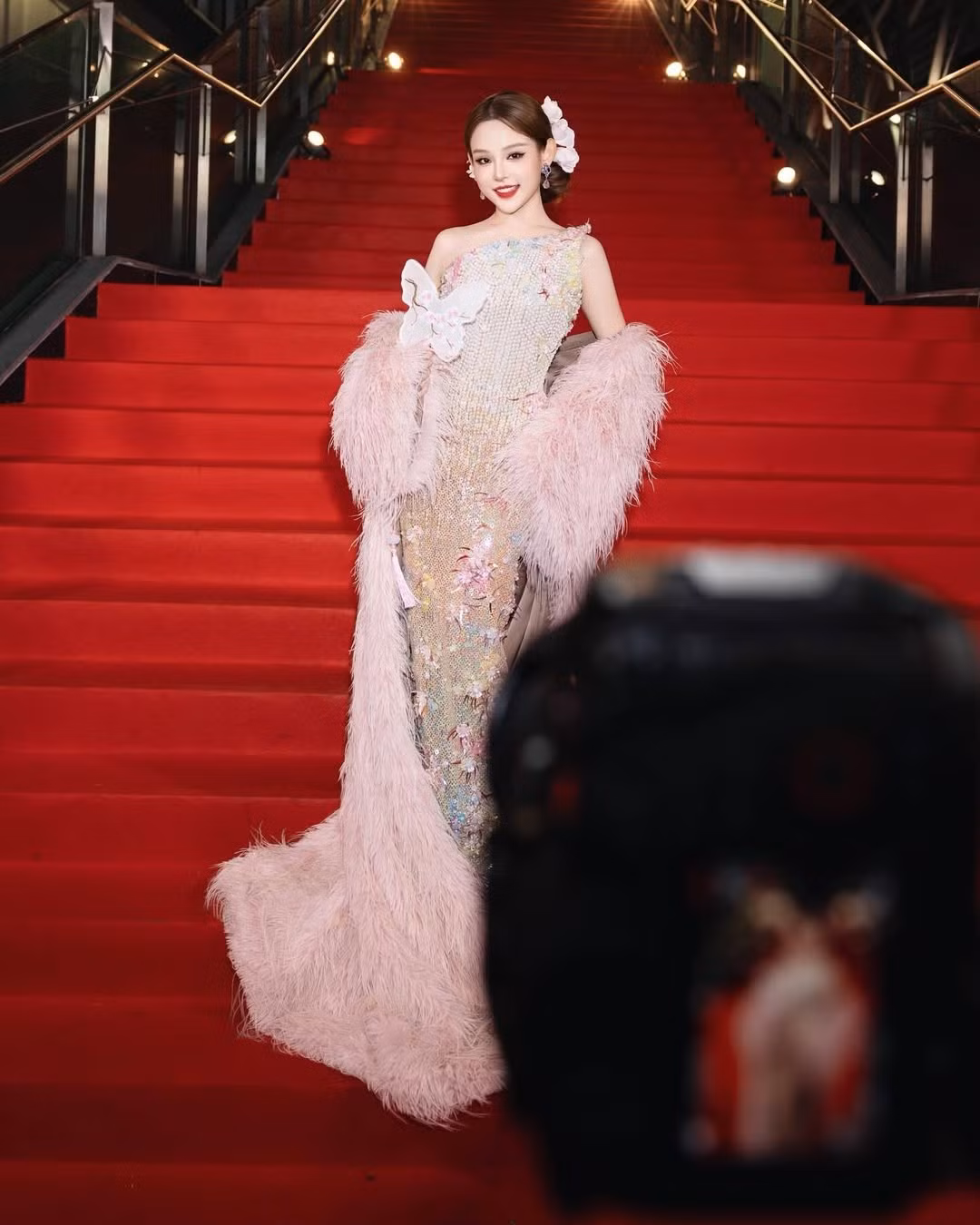 Trên tay cô là chiếc quạt hình bướm được thêu dệt tinh xảo, một món phụ kiện mang đậm nét Á Đông đương đại, hoàn thiện tổng thể diện mạo kiêu sa. (Ảnh: IGNV)