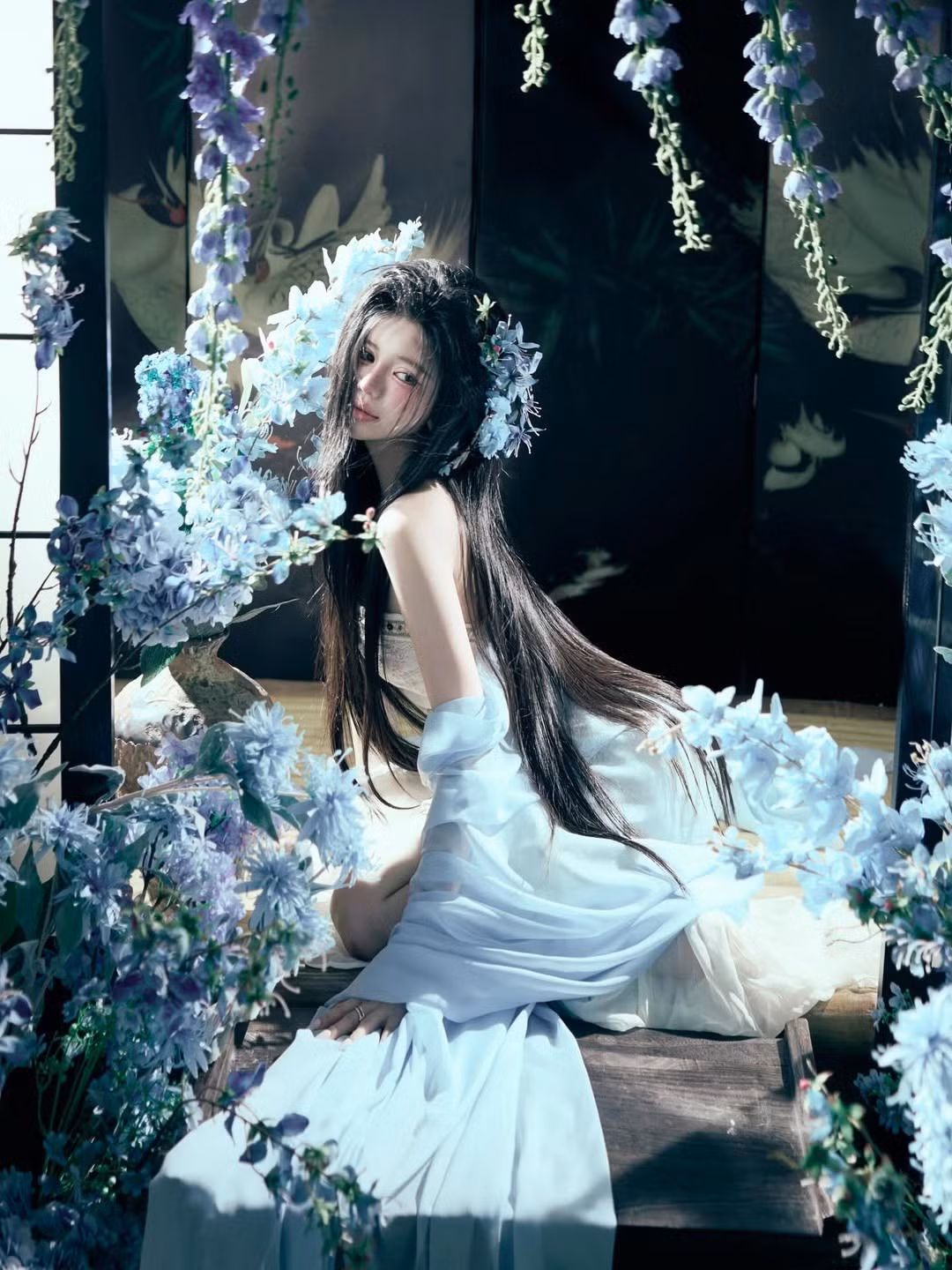 Mái tóc đen dài được tô điểm bằng những đóa hoa cùng tông, tạo nên vẻ đẹp huyền ảo, vừa mong manh vừa quyến rũ. (Ảnh: IGNV)