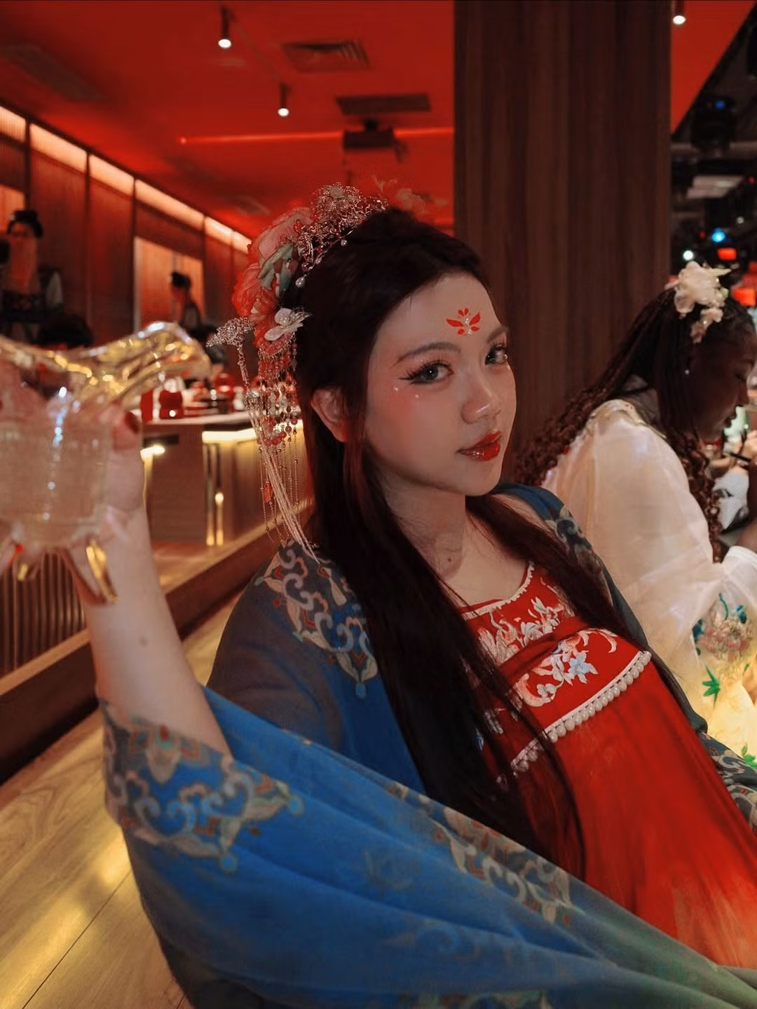 Chiếc áo yếm màu đỏ thêu hoa tinh tế kết hợp cùng lớp áo choàng mỏng màu xanh có họa tiết hoa văn đậm chất Á Đông đã tạo nên một tổng thể vừa duyên dáng vừa kiêu sa. (Ảnh: IGNV)