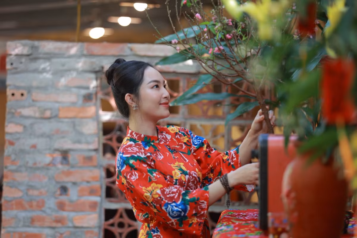 Bộ ảnh được thực hiện trong một không gian đậm chất xưa cũ với tivi đen trắng, điện thoại bàn quay số, phích nước Rạng Đông và những nhành đào xuân. Sự kết hợp này mang lại cảm giác ấm cúng, gợi nhắc về một cái Tết cổ truyền giản dị mà hạnh phúc. (Ảnh: FBNV)