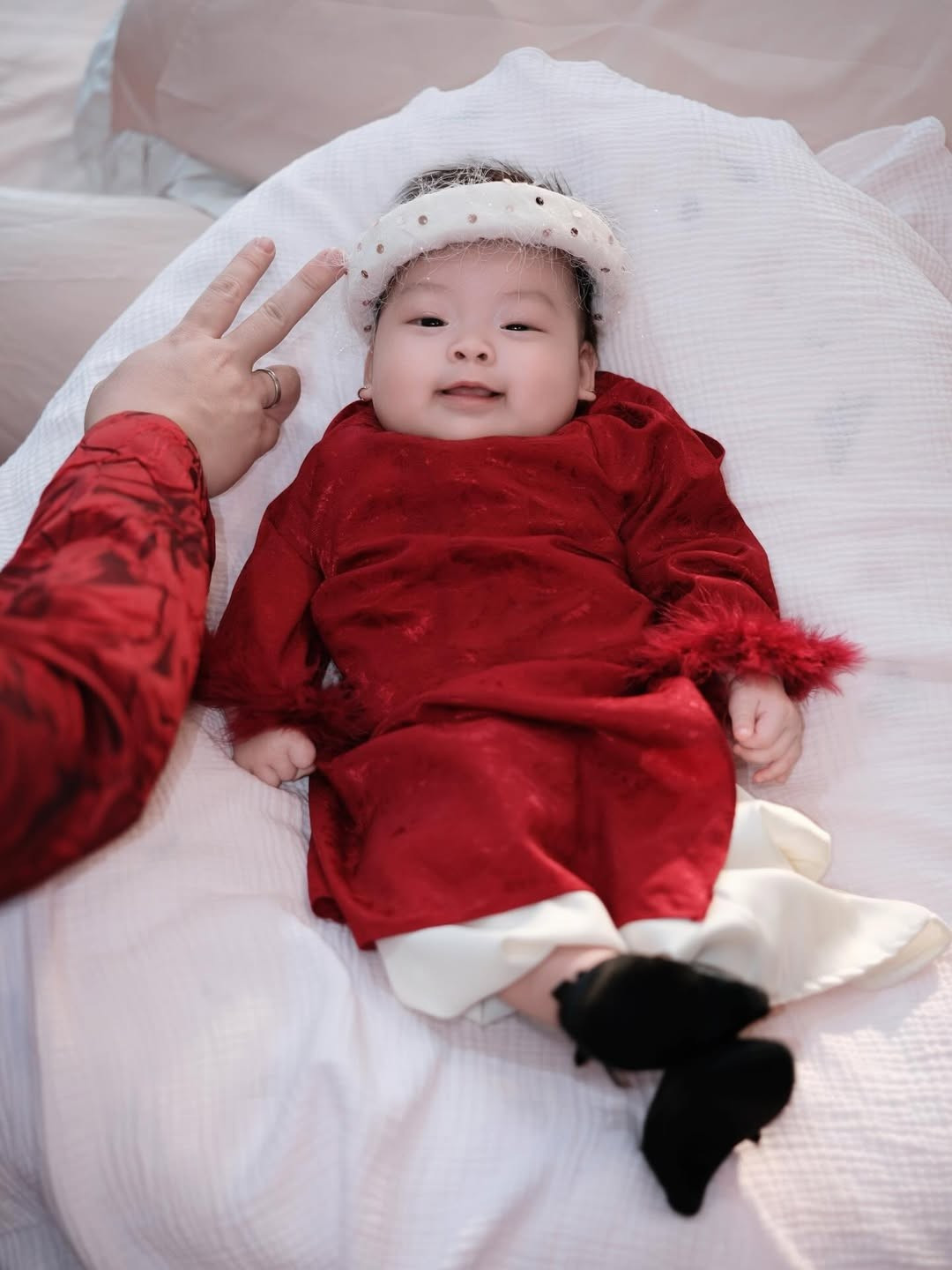 Tâm điểm của bộ ảnh không ai khác chính là em bé kháu khỉnh đang được Thanh Tâm bồng bế trên tay. Bé Bún được mẹ diện một bộ áo dài nhung đỏ "ton-sur-ton" với mình. Đăng kèm với bộ ảnh, cô nàng thể hiện sự hào hứng: "Thấy Bún là thấy Tết". (Ảnh: IGNV)