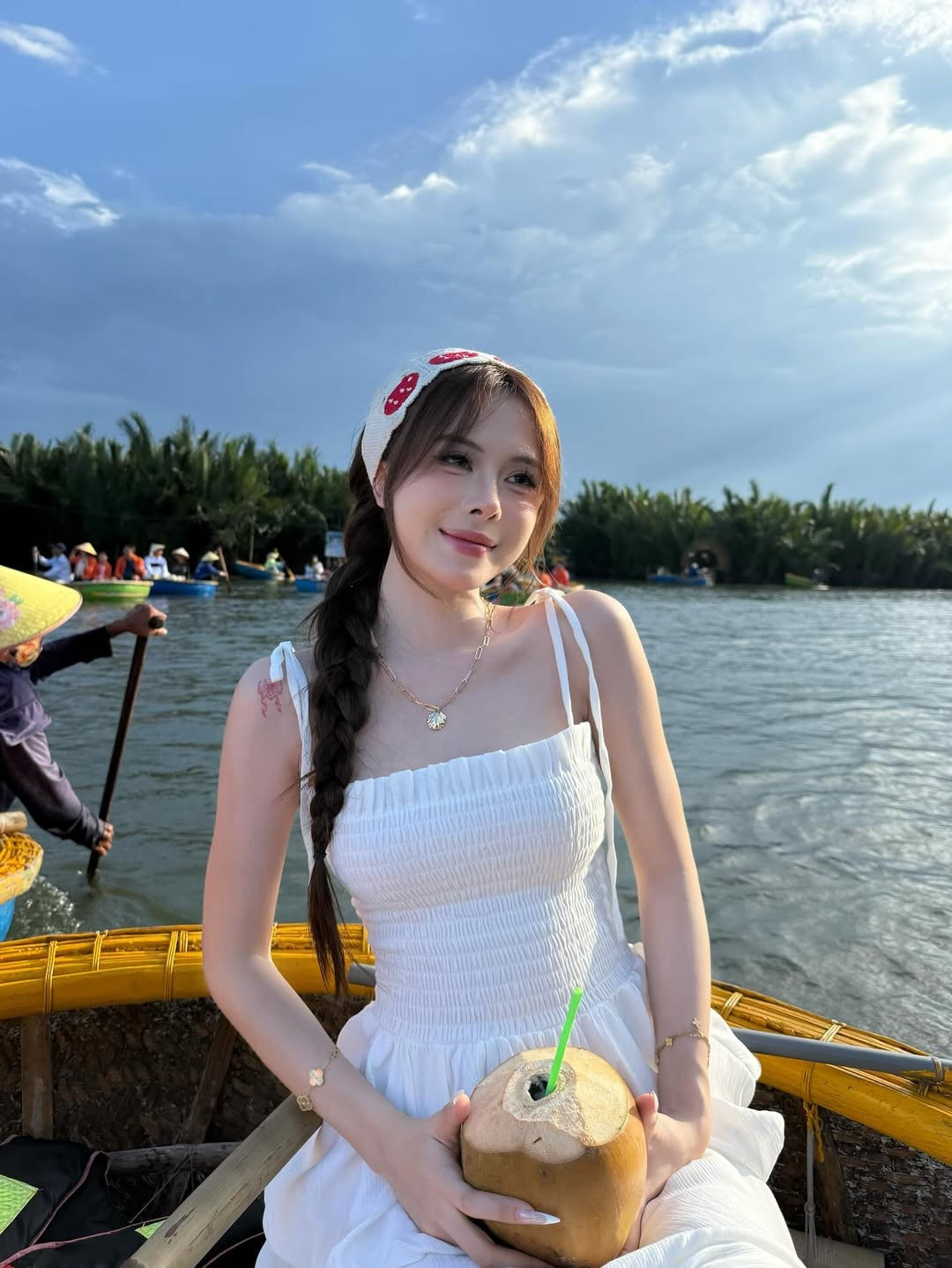 Ngân Hà ngồi trên chiếc thuyền thúng truyền thống, với khung cảnh sông nước hữu tình và hàng dừa xanh ngát phía sau, mang đến cảm giác gần gũi, hòa mình vào thiên nhiên.