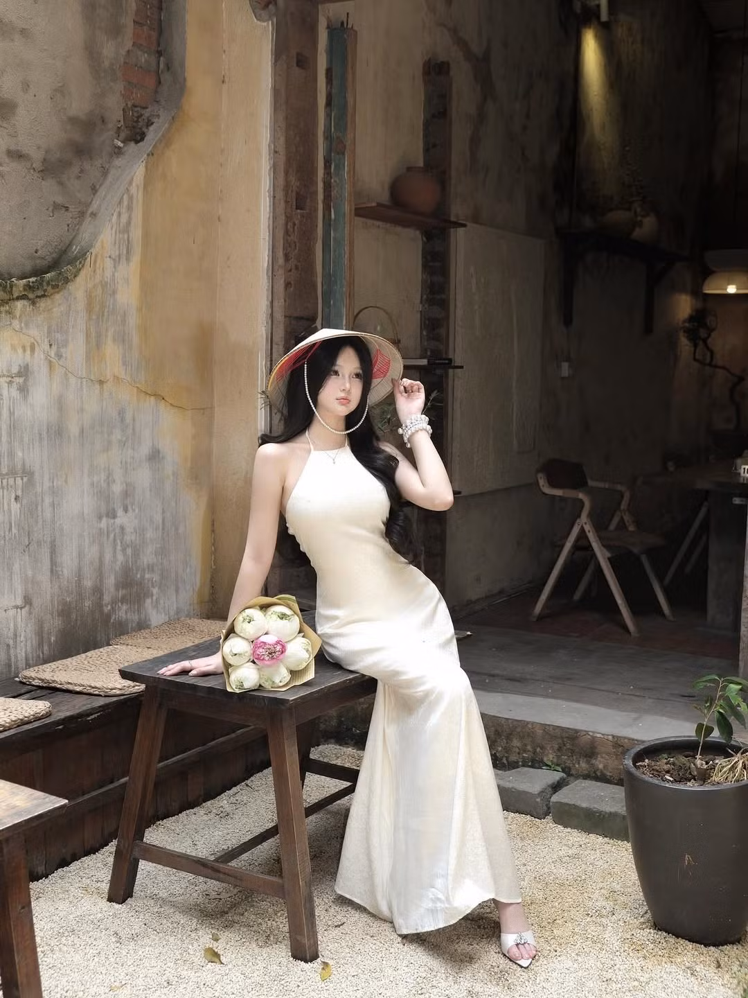 Cô khoác lên mình tà áo yếm màu trắng kem tinh khôi, với thiết kế cổ yếm khoe khéo bờ vai mảnh mai và vóc dáng chuẩn. (Ảnh: IGNV)