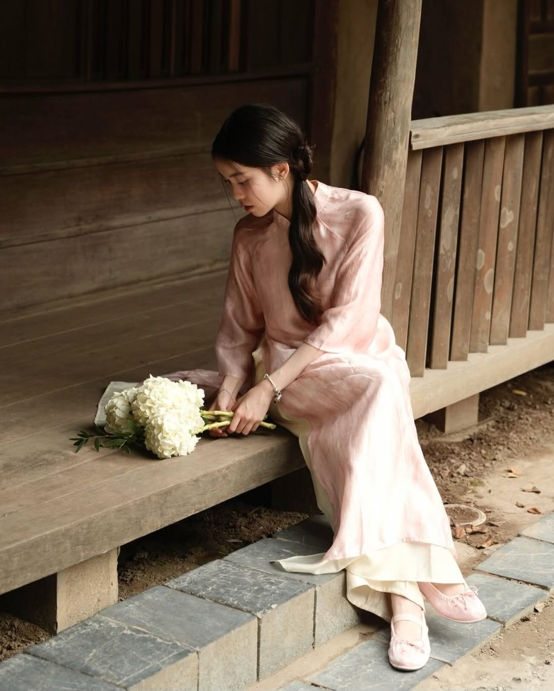 Cô nàng khéo léo phối cùng một bó hoa cẩm tú cầu trắng tinh khôi, tạo nên sự tương phản nhẹ nhàng nhưng cuốn hút với màu áo. Đôi giày búp bê màu hồng nhạt cùng tông với áo là lựa chọn hoàn hảo để hoàn thiện vẻ ngoài này. (Ảnh: IGNV)