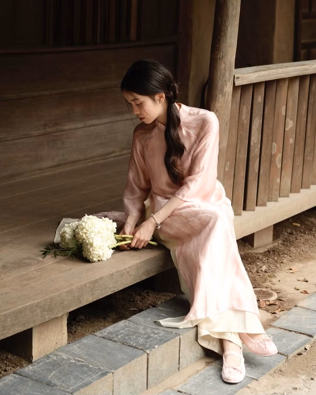 Cô nàng khéo léo phối cùng một bó hoa cẩm tú cầu trắng tinh khôi, tạo nên sự tương phản nhẹ nhàng nhưng cuốn hút với màu áo. Đôi giày búp bê màu hồng nhạt cùng tông với áo là lựa chọn hoàn hảo để hoàn thiện vẻ ngoài này. (Ảnh: IGNV)