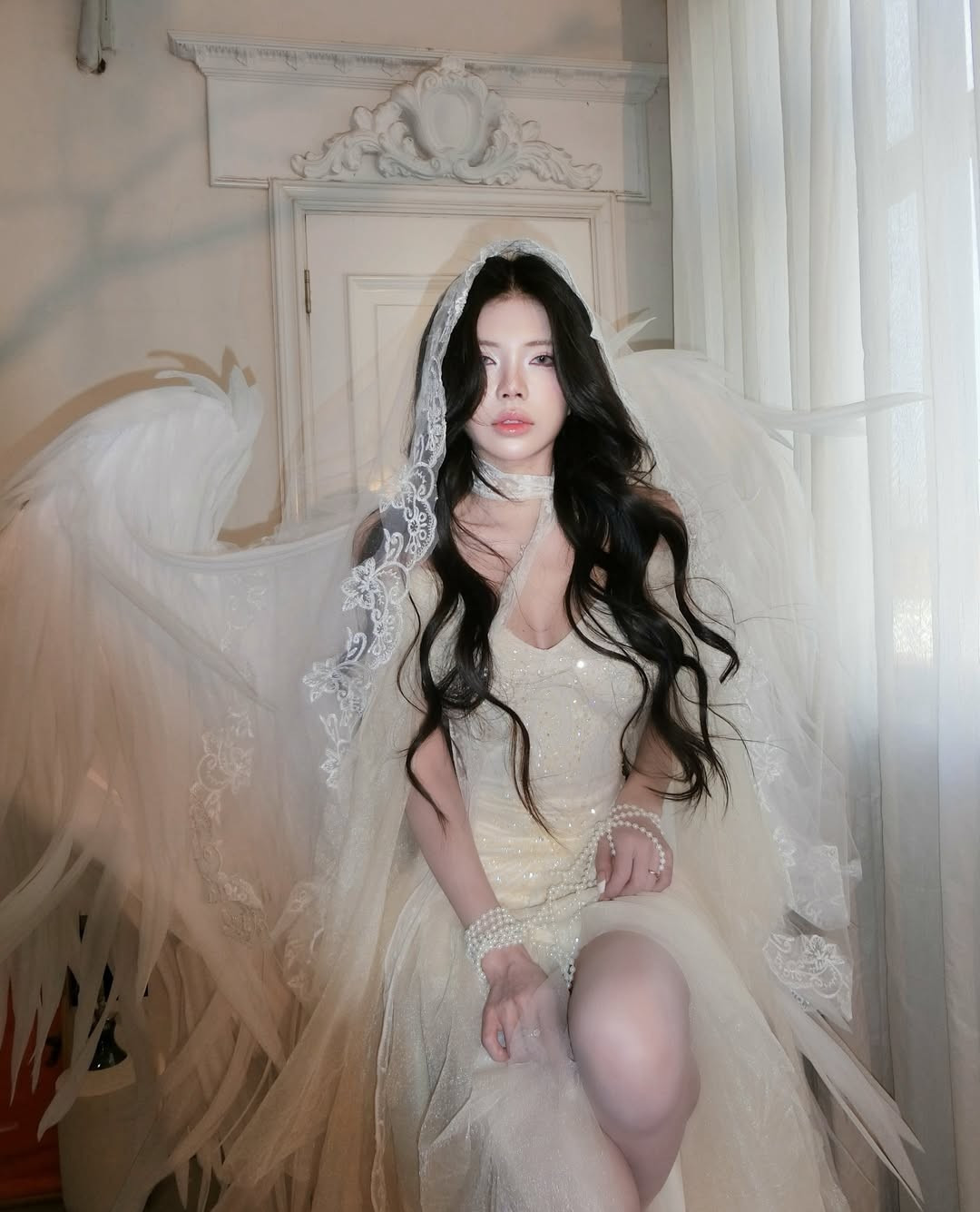 Chuỗi vòng ngọc trai quấn quanh cổ tay và chân không chỉ là điểm nhấn sang trọng mà còn tạo cảm giác như những "xiềng xích" nghệ thuật, tăng thêm phần bí ẩn cho bộ ảnh.