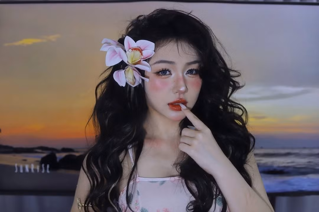 Nàng hot girl áp dụng lối trang điểm đậm chất "Tây", với lớp nền trắng sáng, đôi mắt to tròn được nhấn nhá kỹ lưỡng bằng lens và eyeliner sắc sảo. Đặc biệt là phần má hồng đánh cao và đậm, tạo hiệu ứng say nắng, cùng đôi môi đỏ mọng quyến rũ. Lối trang điểm này mang lại vẻ đẹp vừa hiện đại, vừa có chút bí ẩn, khác lạ.