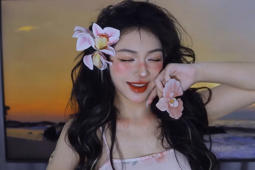 Cô nàng lựa chọn một chiếc váy hai dây màu hồng nhạt, với họa tiết hoa lá nhỏ nhắn, tạo cảm giác nhẹ nhàng, bay bổng. Kiểu dáng đơn giản nhưng thanh thoát, phù hợp với không khí lãng mạn của biển cả.