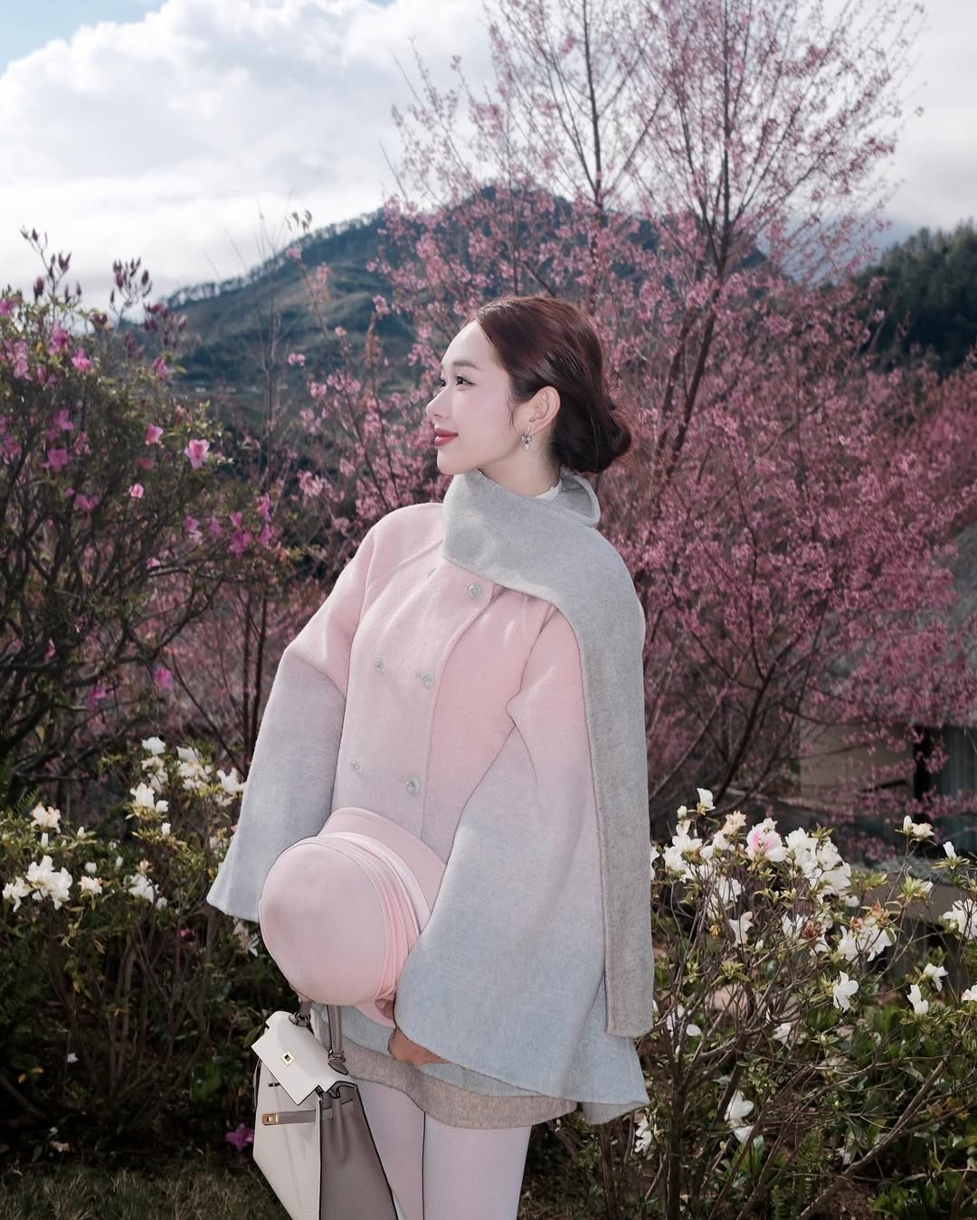 Dù không tiết lộ chính xác tọa độ, nhưng qua những hình ảnh đồi chè xanh mướt điểm xuyết hàng mai anh đào hồng rực, nhiều "tín đồ dịch chuyển" đoán rằng cô nàng đang check-in tại Đồi chè Ô Long (Sapa) hoặc vùng Mộng Đào Nguyên (Lạc Dương, Đà Lạt) - hai trong số những địa điểm ngắm mai anh đào đẹp nhất năm 2026. (Ảnh: FBNV)